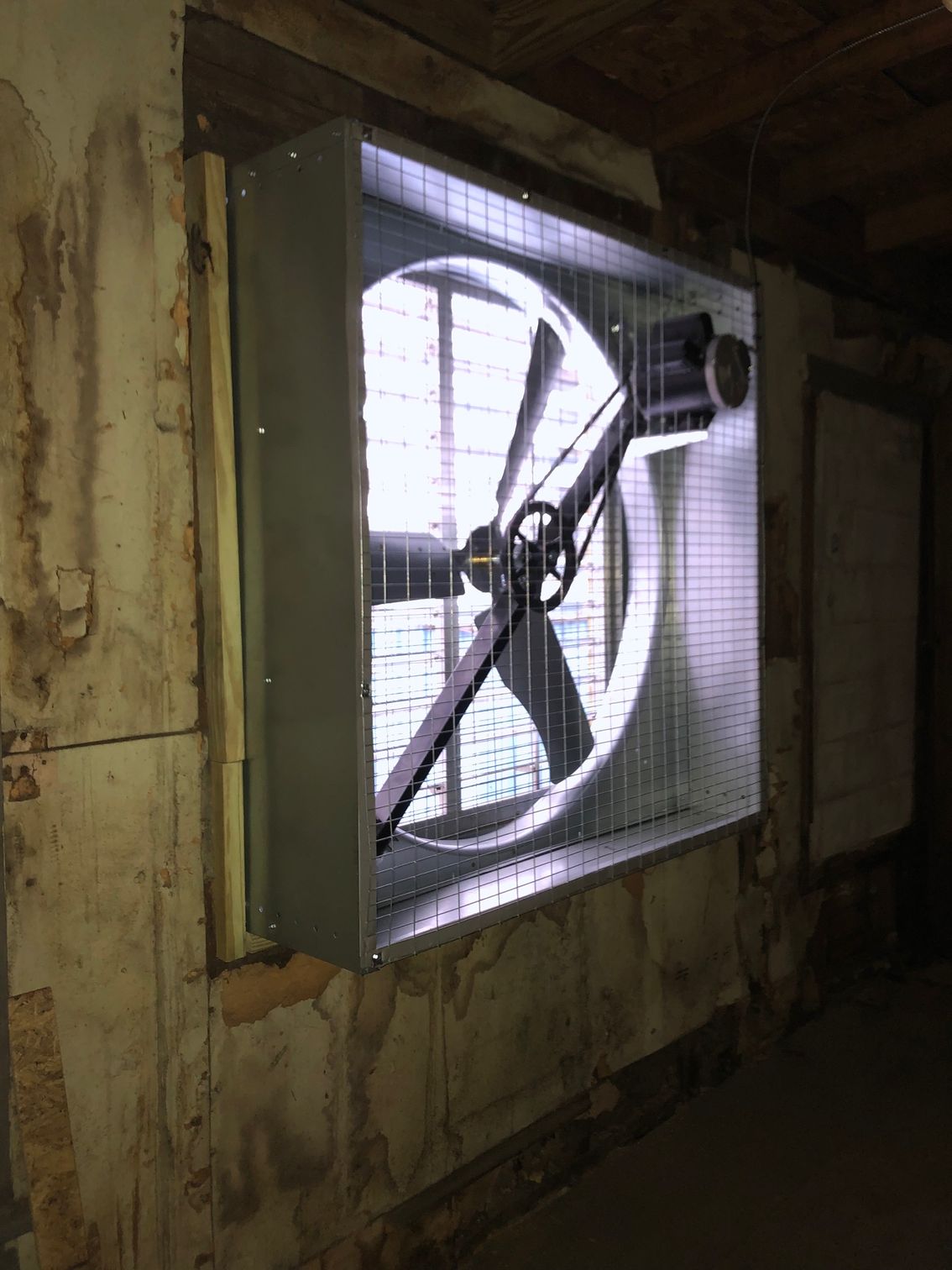 a large fan is hanging on a wall in a room