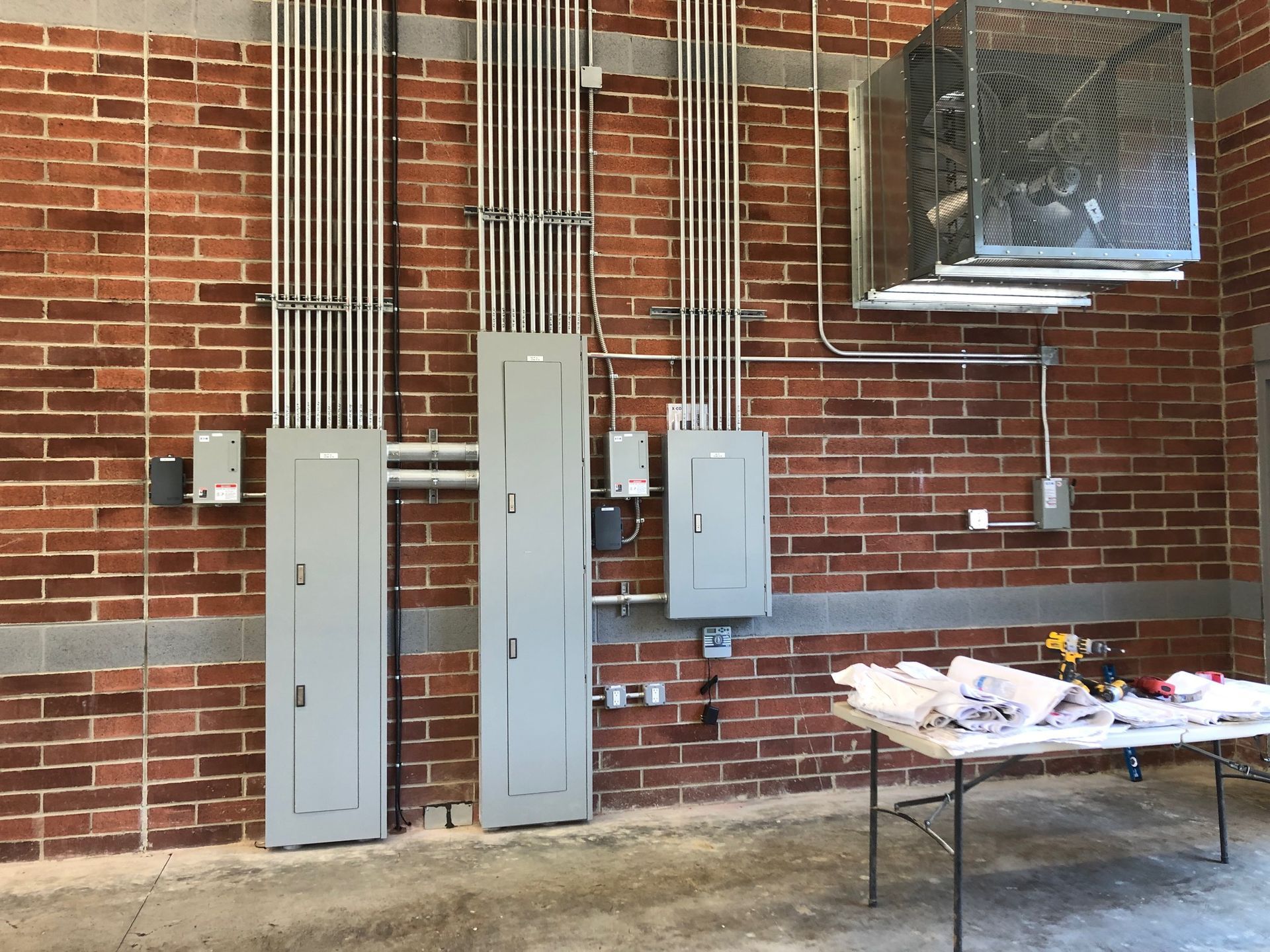 a brick wall with electrical panels and a table in front of it