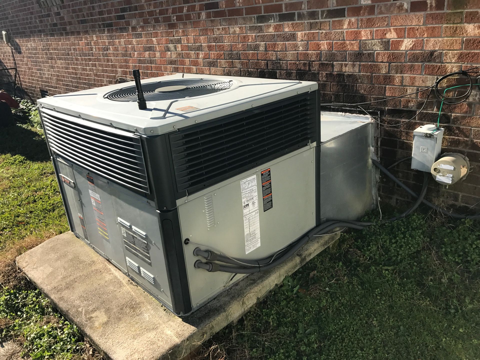 a large air conditioner is sitting outside of a brick building 