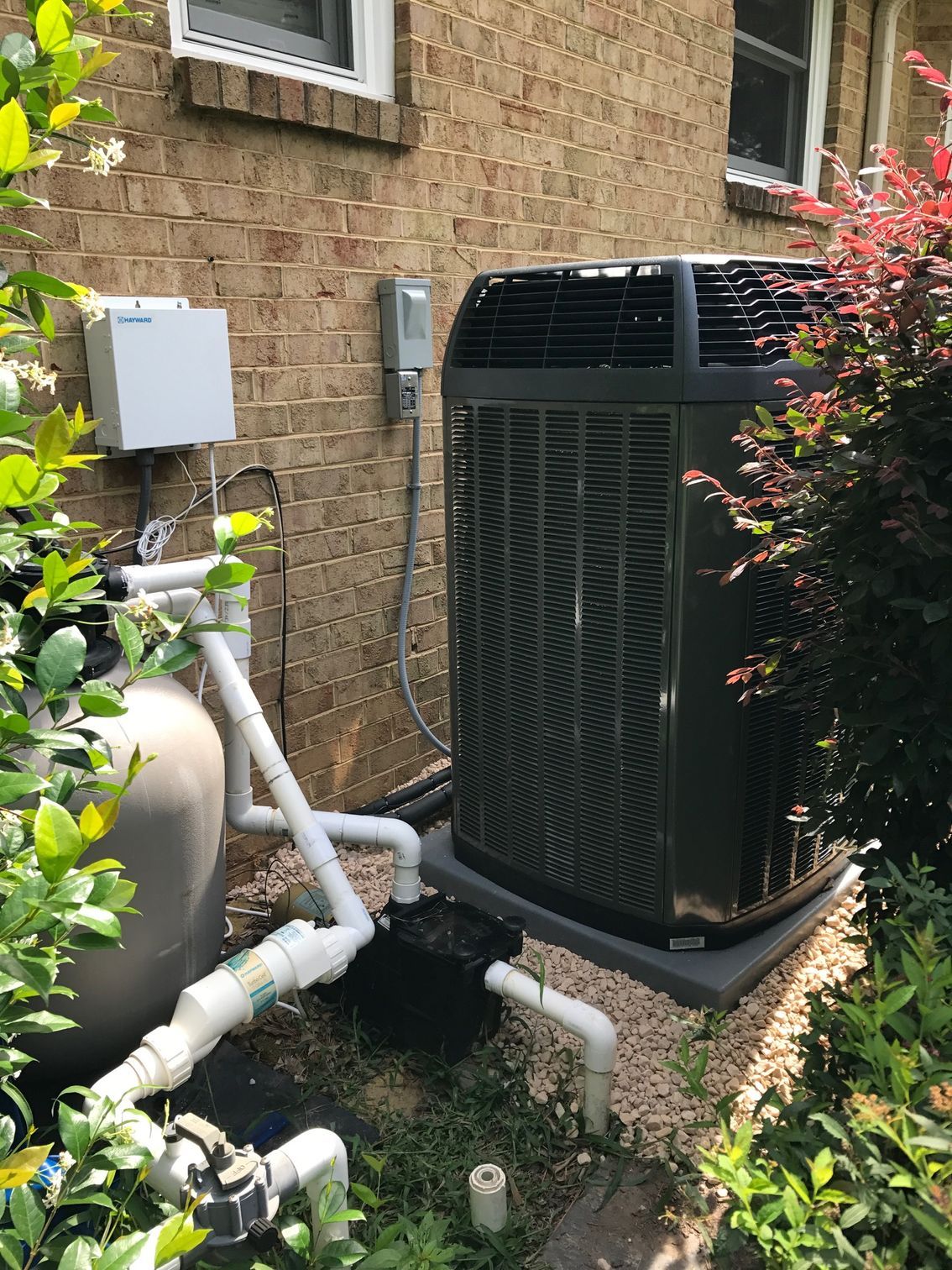 a large air conditioner is sitting outside of a brick building next to a pool pump 