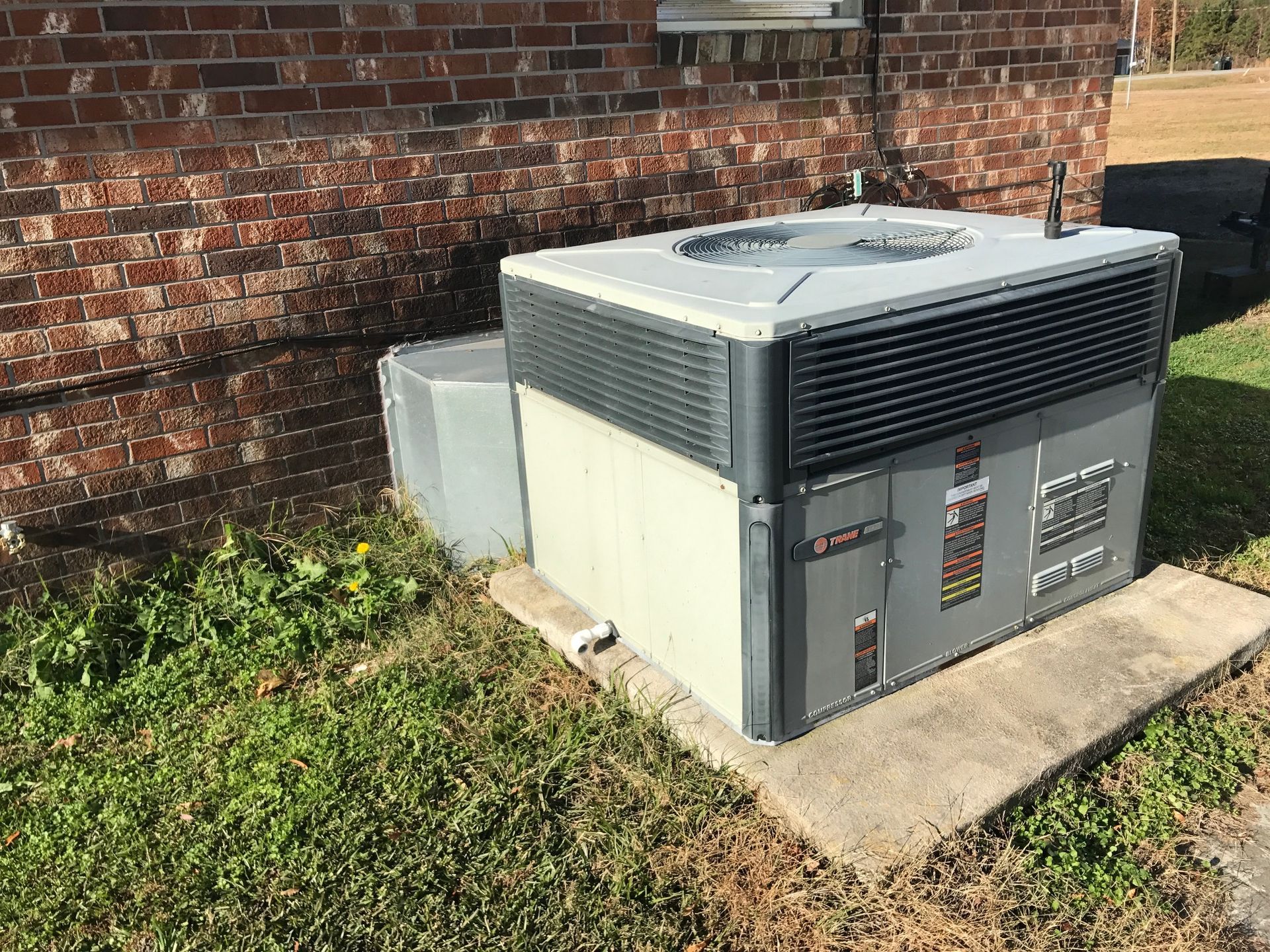 a large air conditioner is sitting in the grass in front of a brick building 