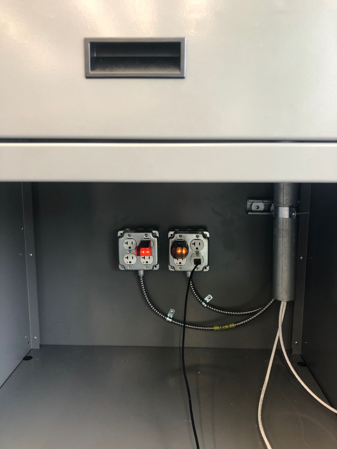 two electrical outlets are plugged into a wall under a cabinet