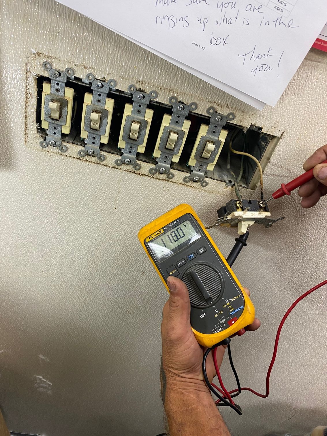 a person is holding a multimeter in front of a wall