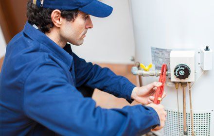 Learn More About Water Heaters Plumber fixing a hot-water heater