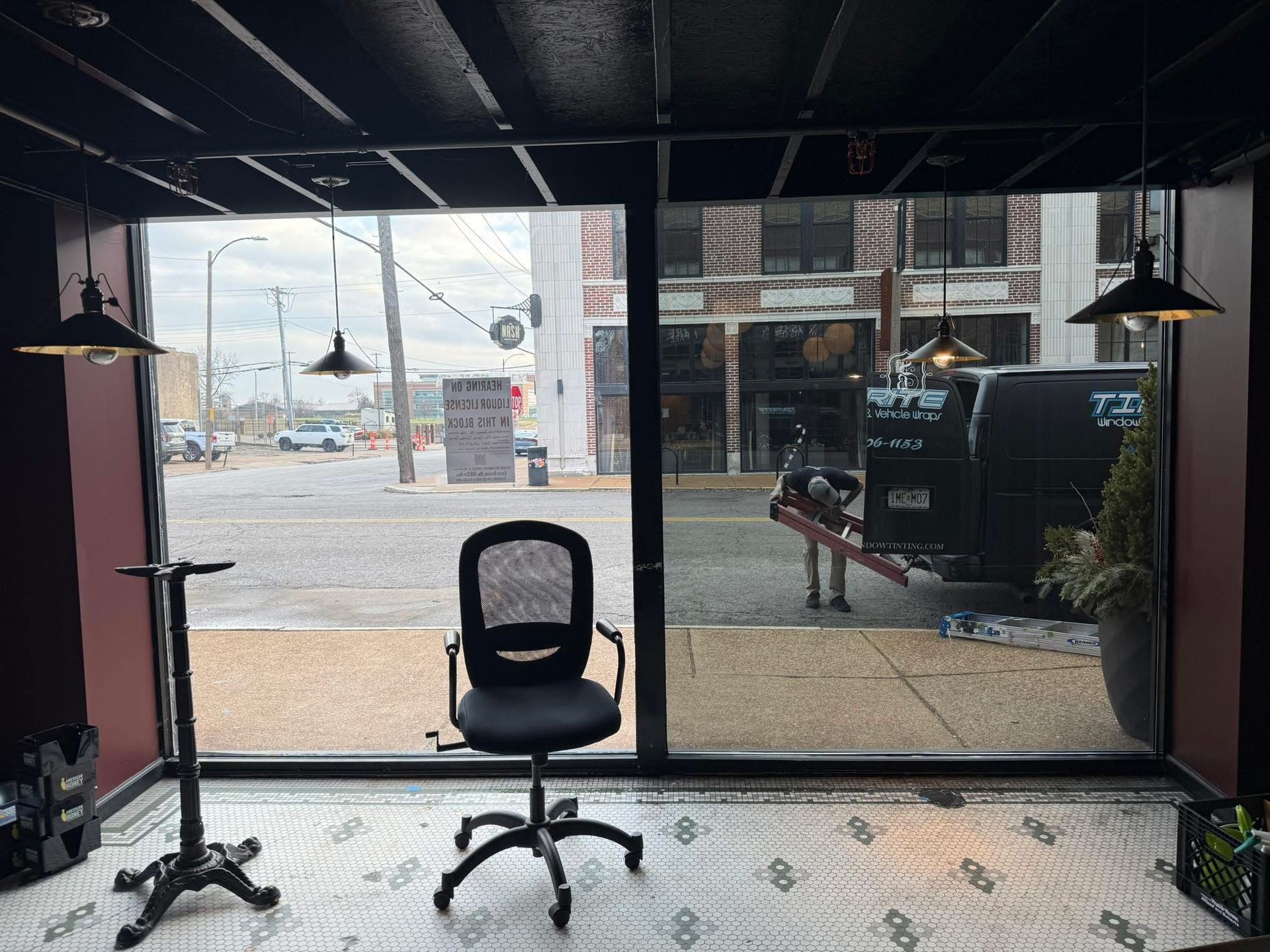 Empty office with a black chair facing large windows and an outdoor street view.