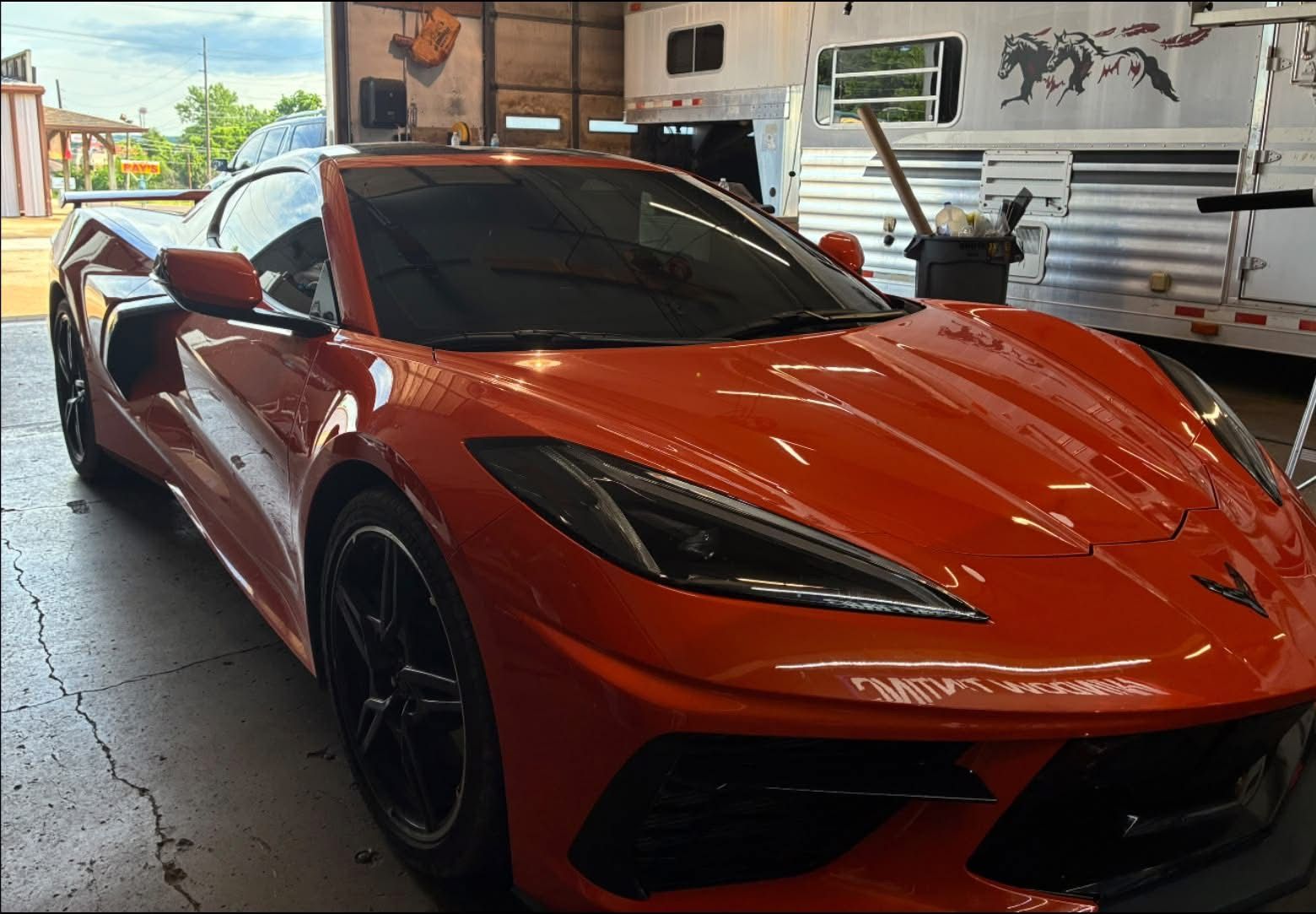 Orange sports car parked in a garage, viewed from the front-left angle.