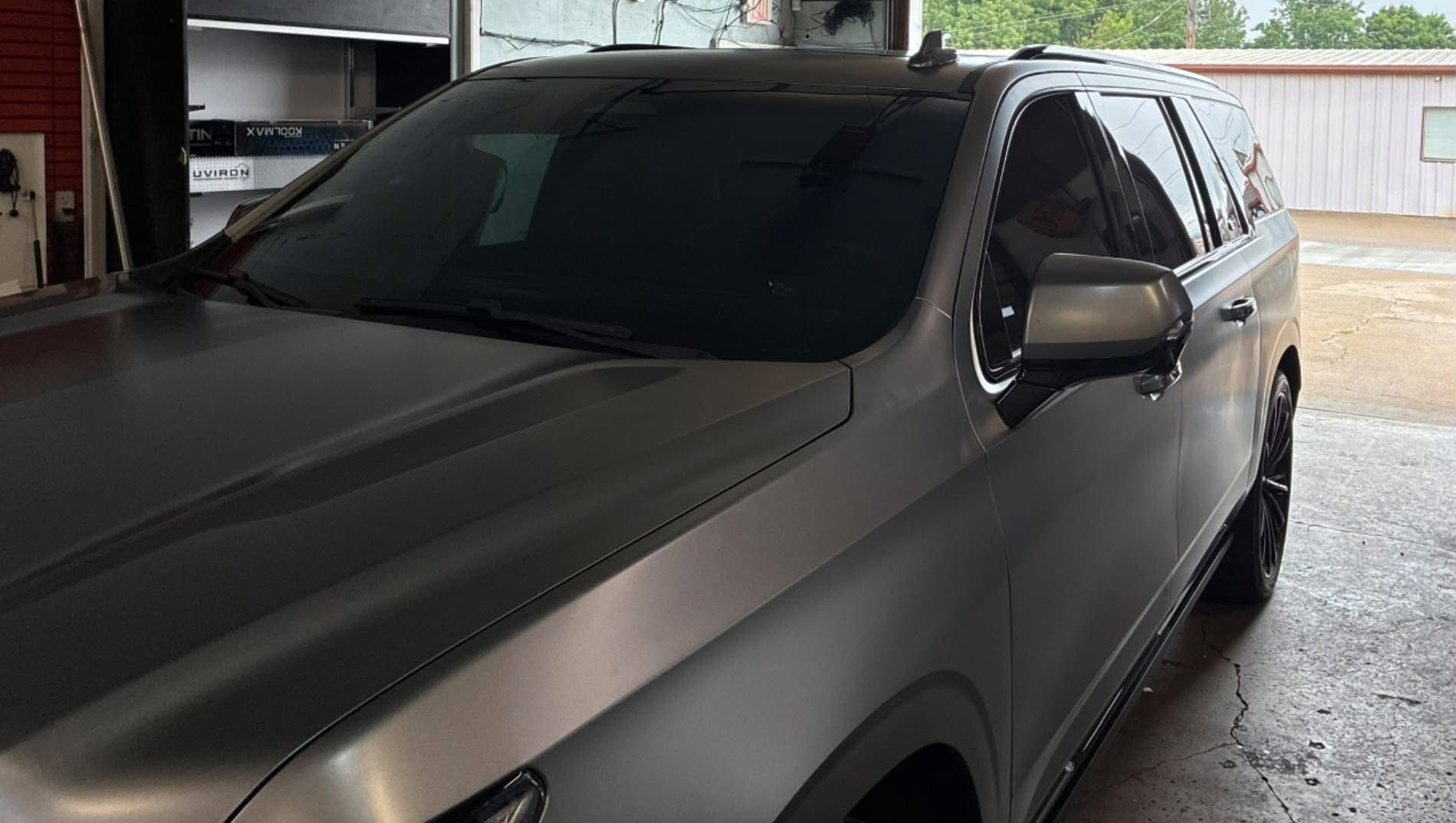 Dark gray SUV parked in a garage, viewed from the front-left side.