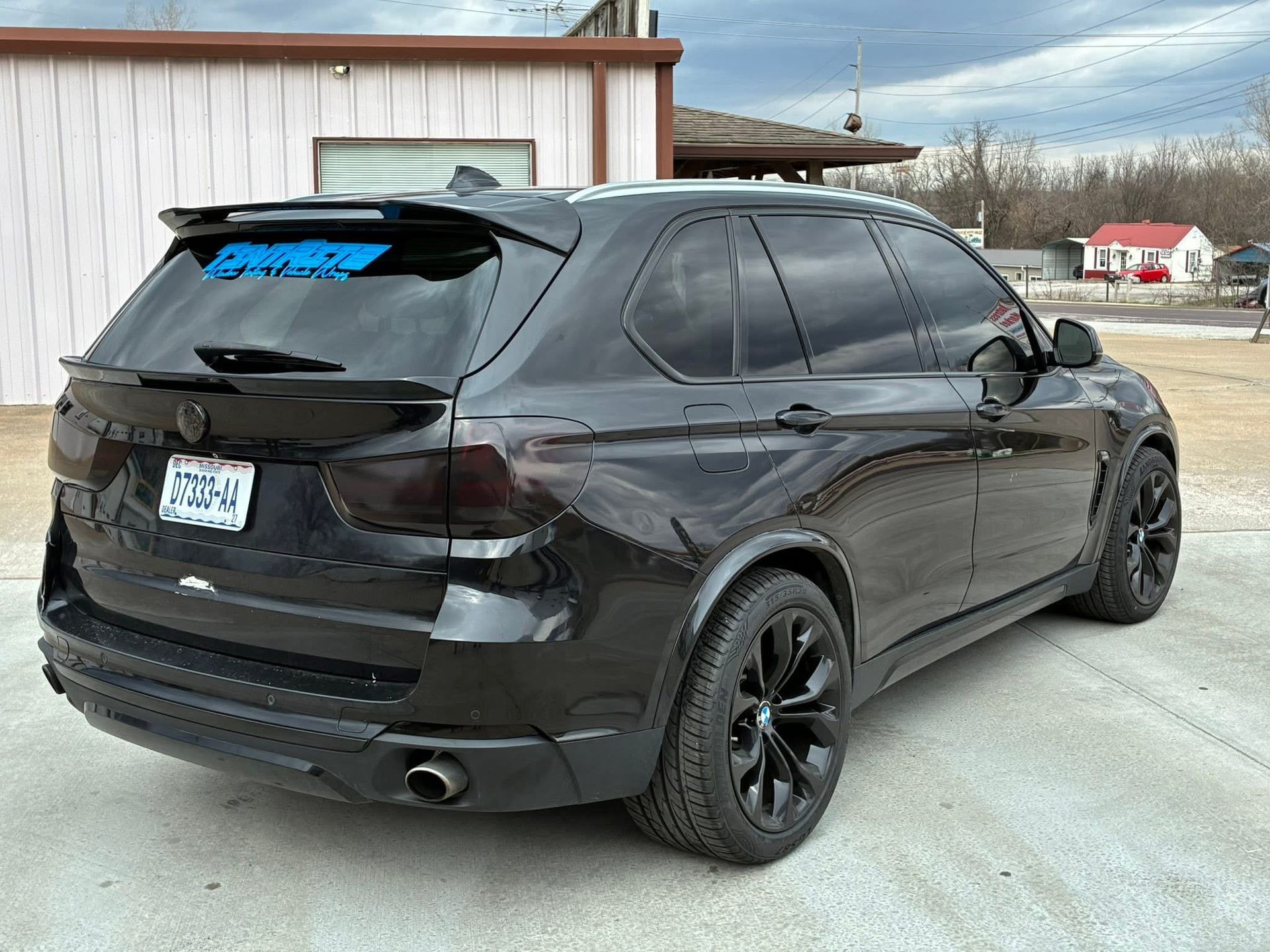Black SUV parked outdoors beside a building on a cloudy day