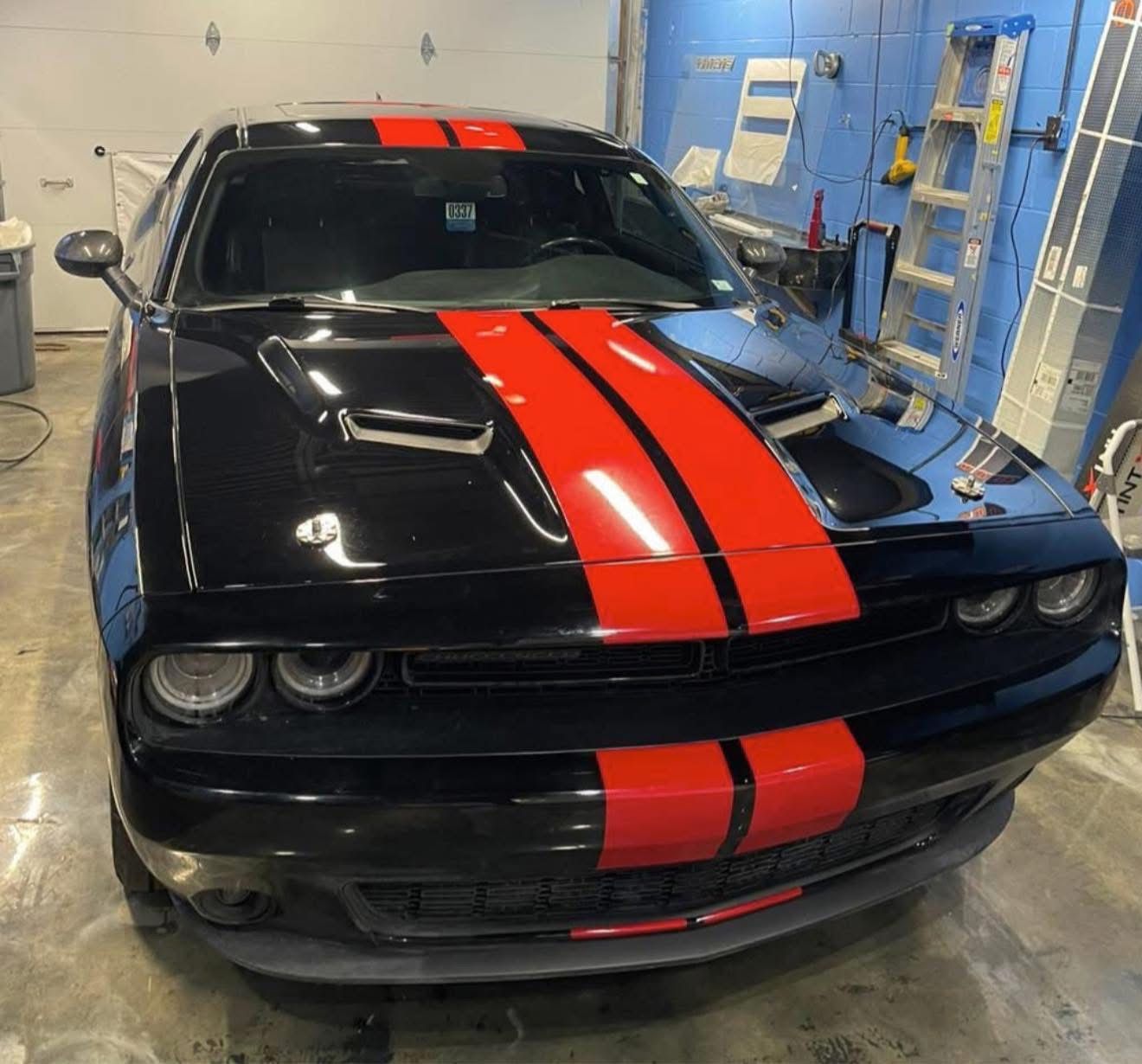 Black sports car with red racing stripes parked in a garage
