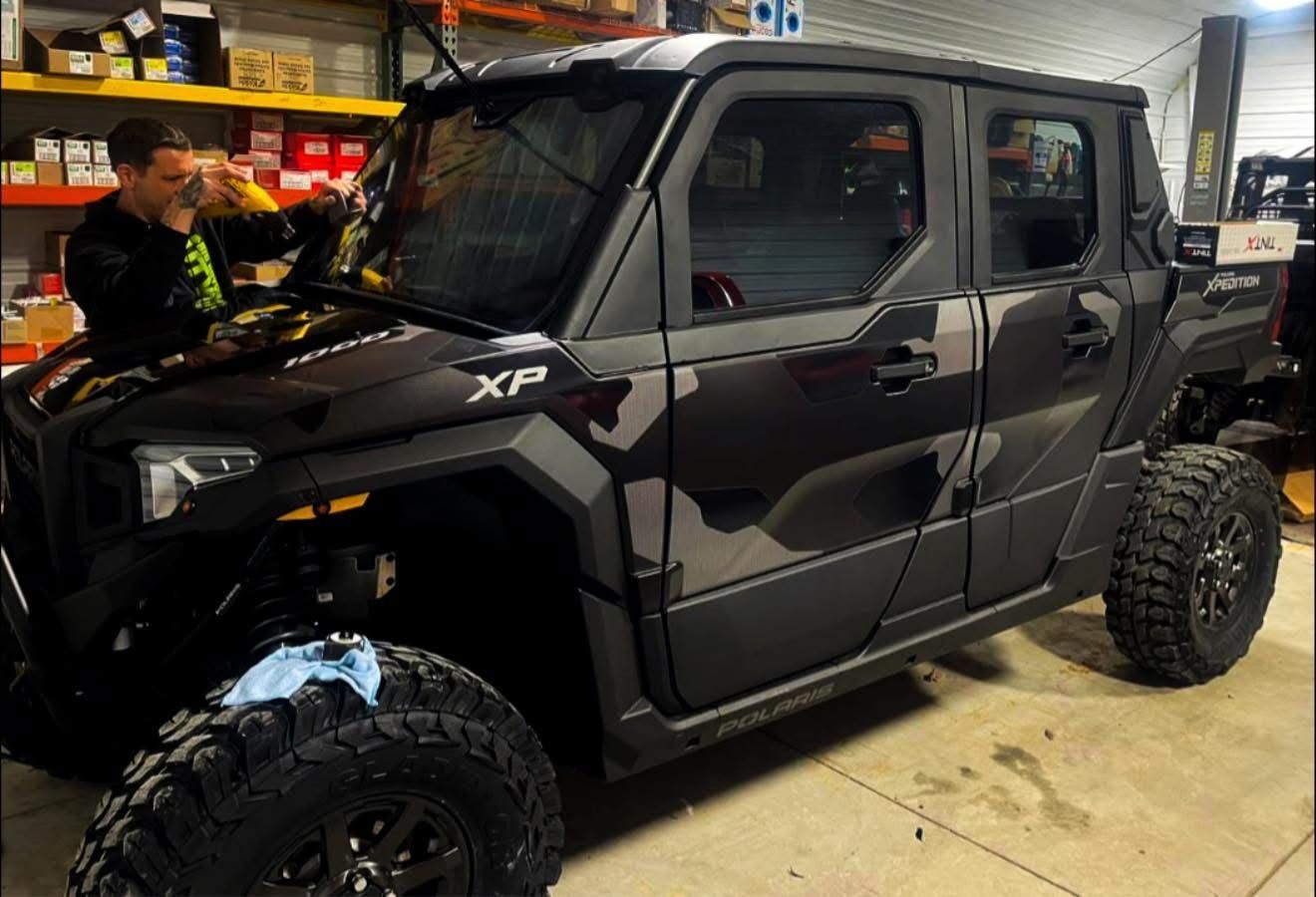 Black off-road SUV in a garage, with a person working beside it.