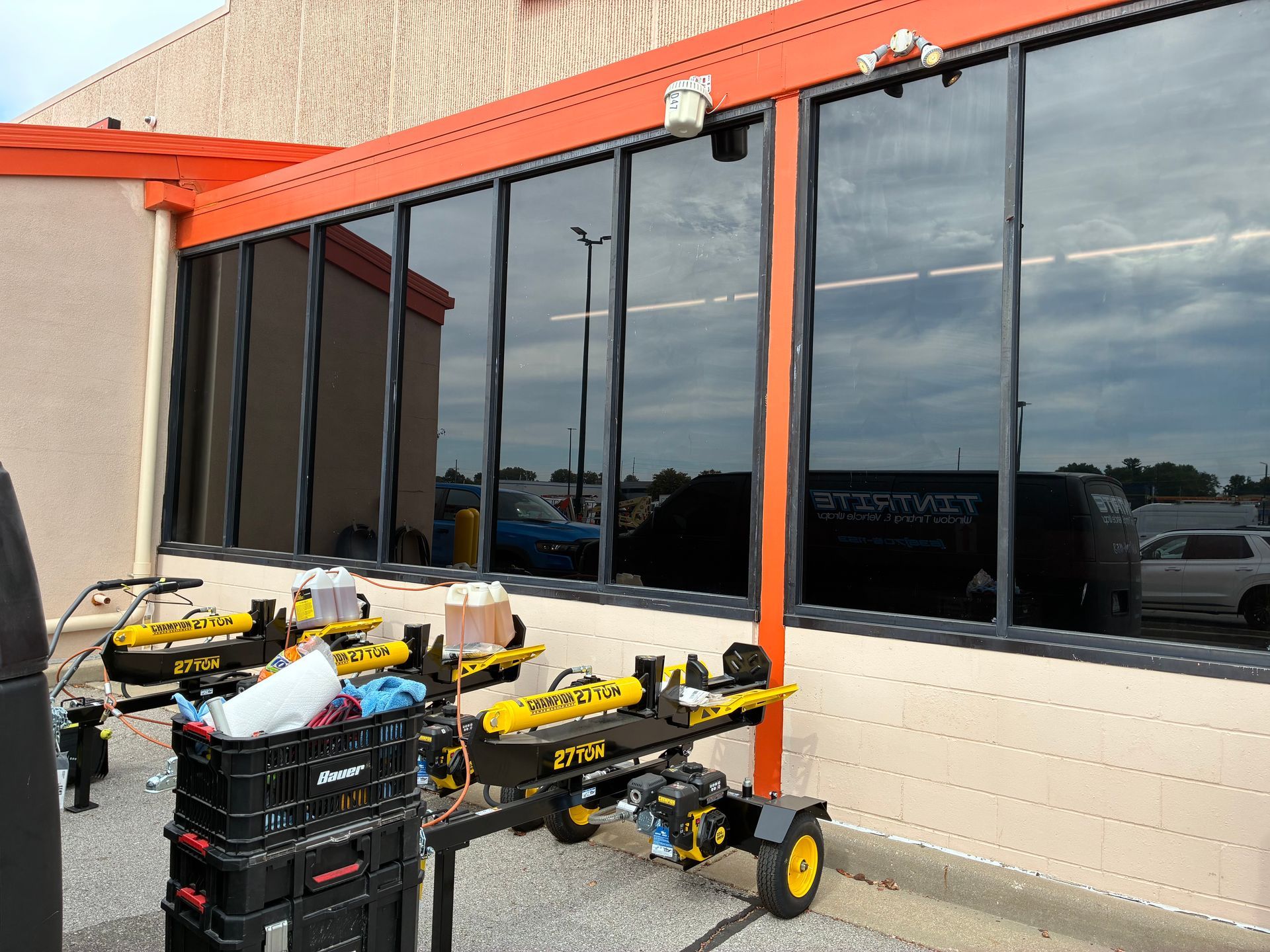 Storefront with orange awning, black-framed windows, and carts and equipment stacked outside
