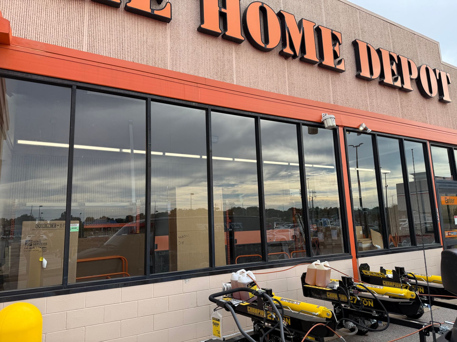Home Depot storefront with large windows and yellow lawn equipment parked outside