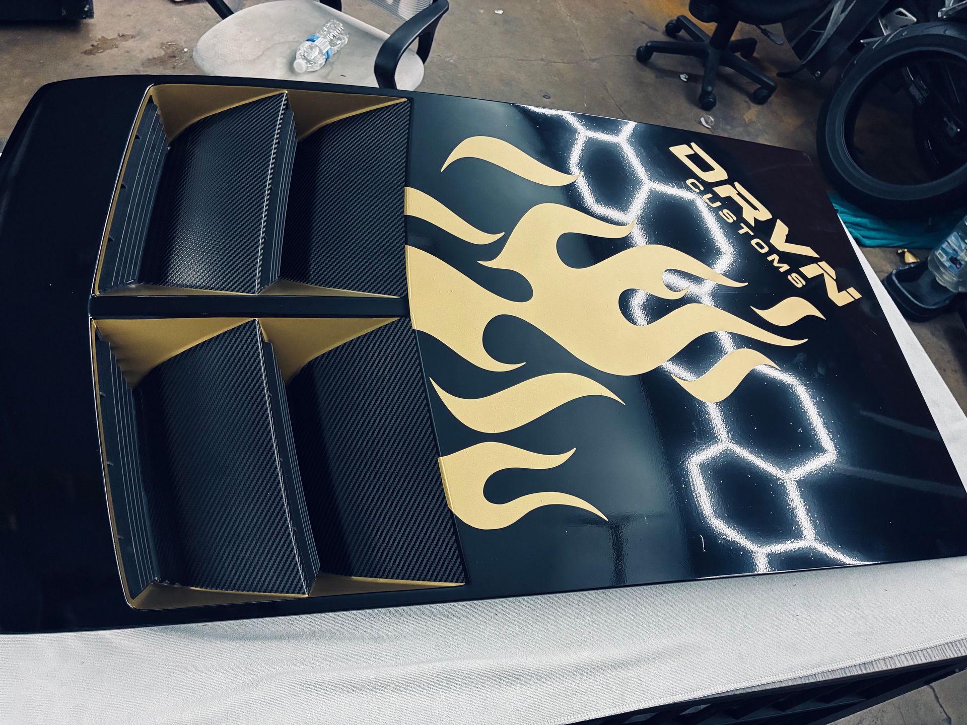 Black car with gold flame decals and white lightning graphics on a worktable