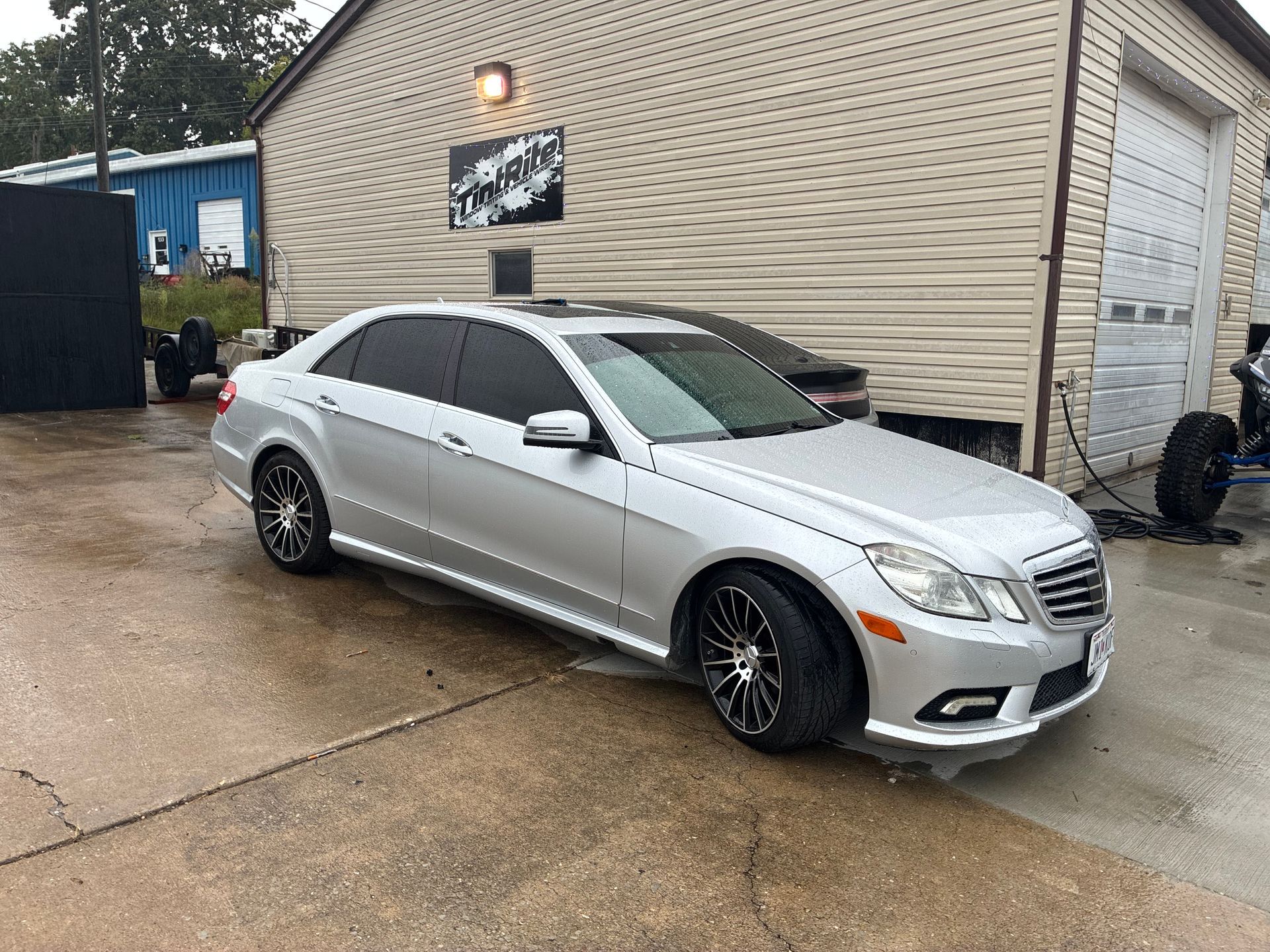 Silver sedan parked outside a beige building on a wet lot