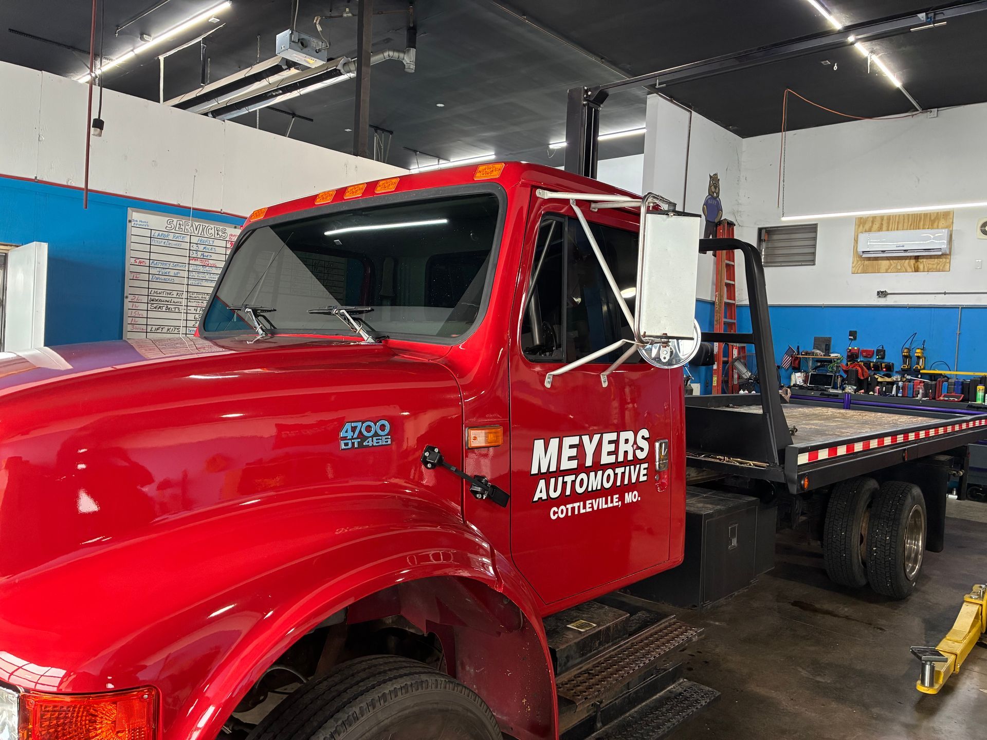 Red tow truck in a garage with Meyers Automotive lettering on the door