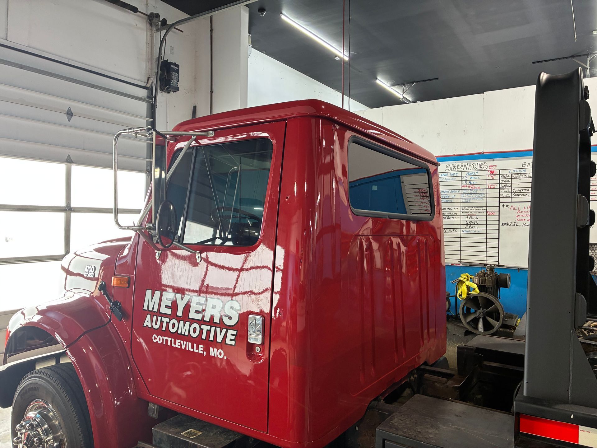 Red vintage automotive tow truck cab inside a garage, with white lettering on the door.