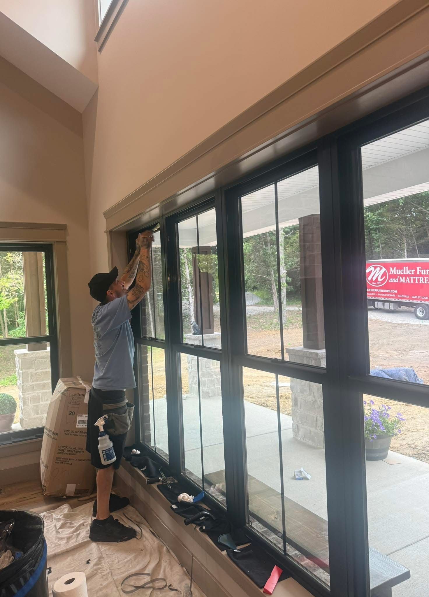 Worker installing black glass sliding doors in a bright indoor space