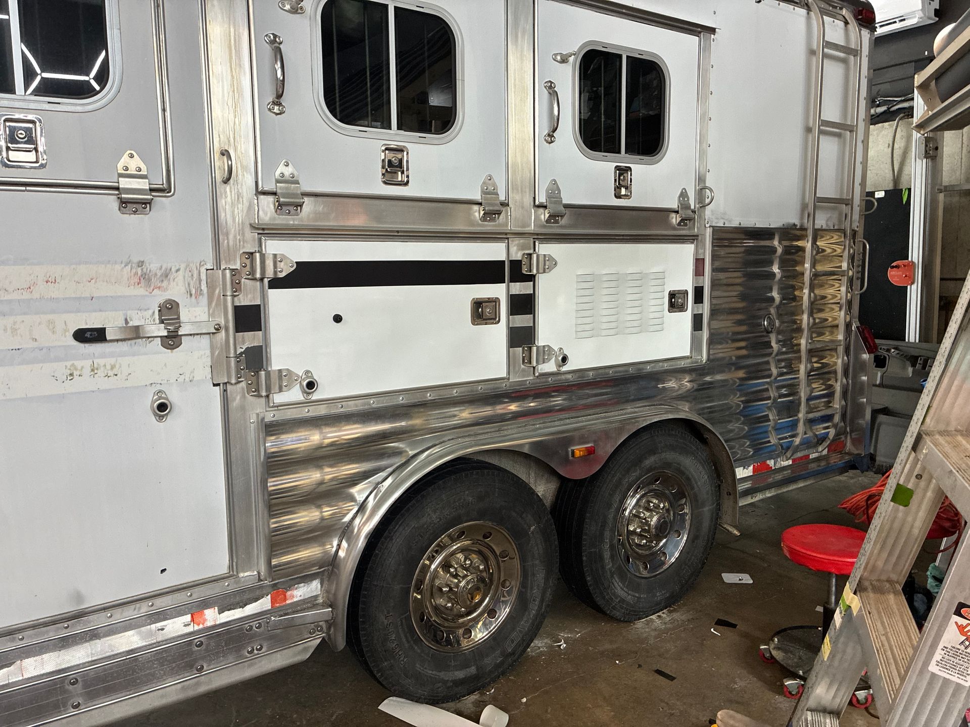 White semi-truck cab parked in a garage, showing dual rear wheels and chrome trim.