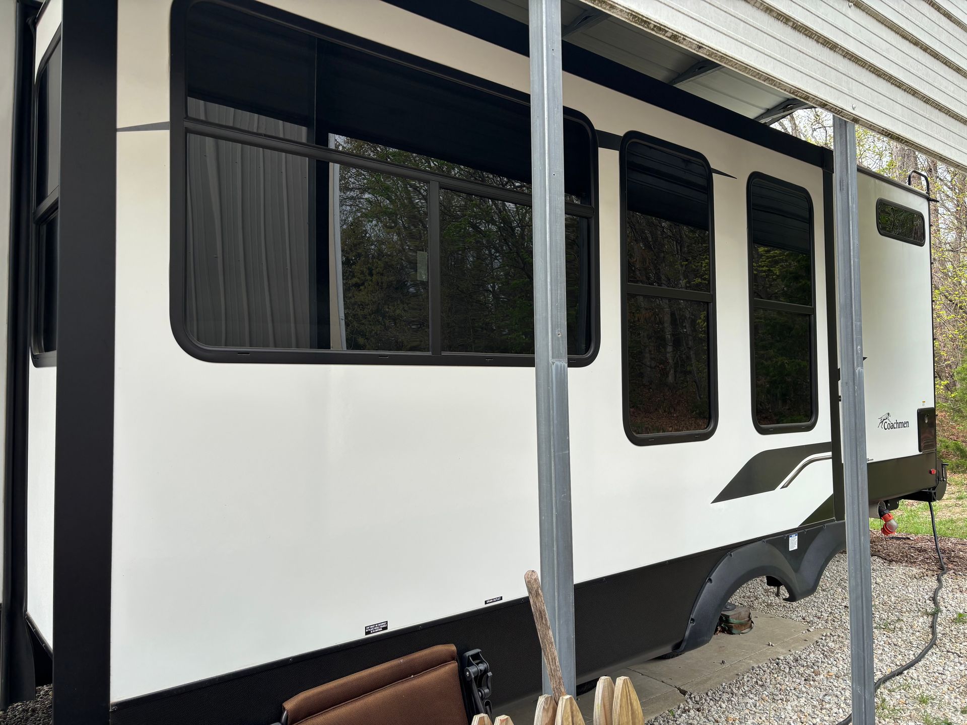 White and black RV trailer parked outdoors with a side awning and windows