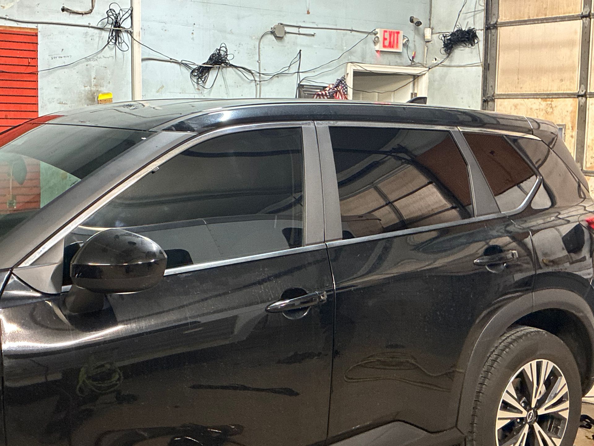 Black SUV parked indoors near a garage wall and door