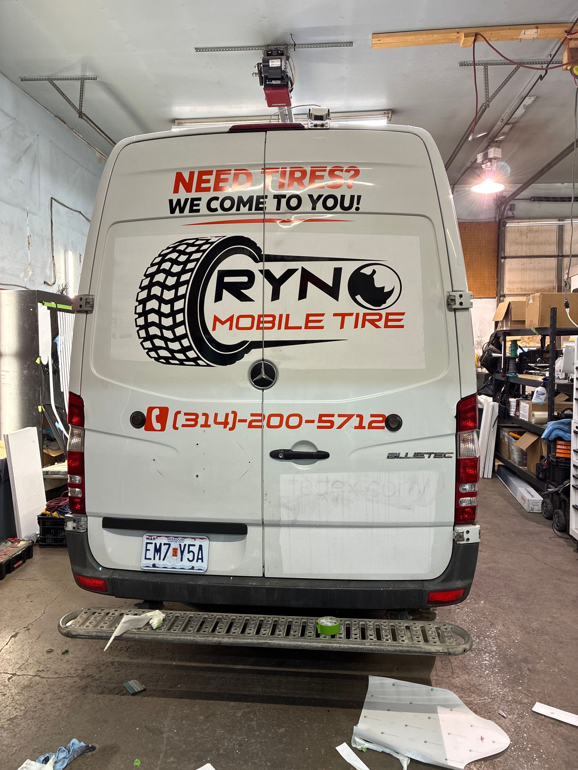 Rear view of a white Ryno Mobile Tire van parked indoors with bold red and black company branding.