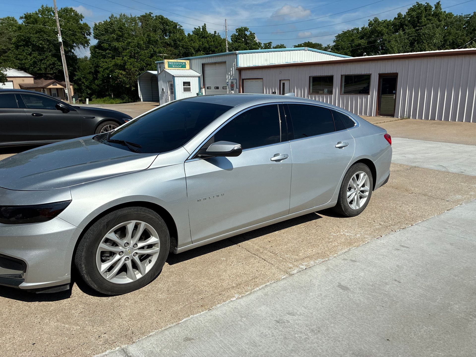 Silver sedan parked outside a low building on a sunny day
