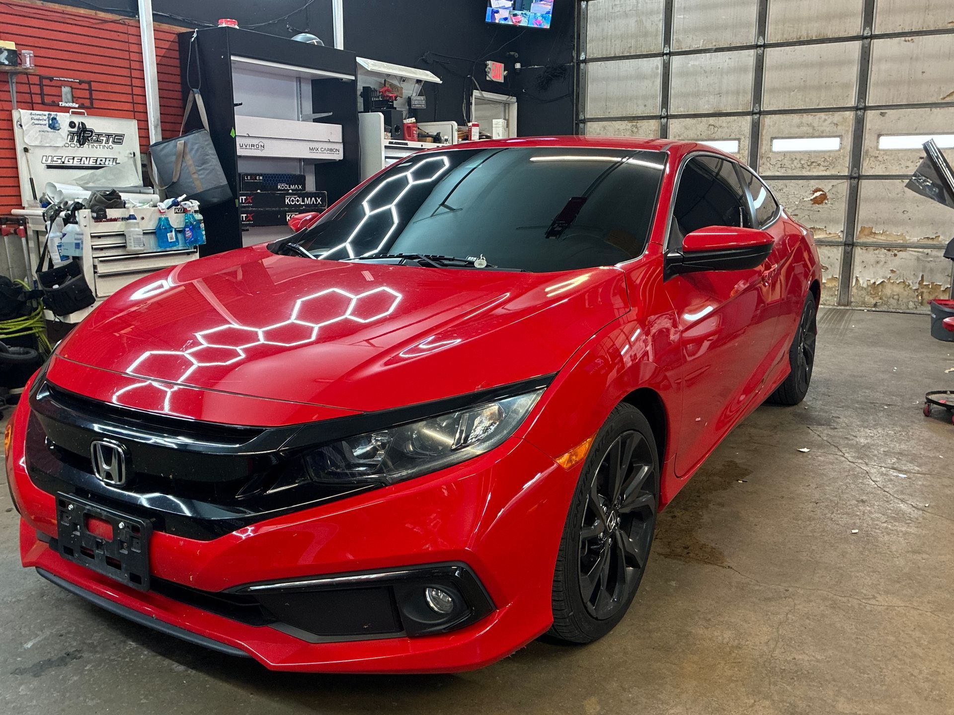 Red Honda Civic in an auto shop, front-left view, with glossy paint and black rims