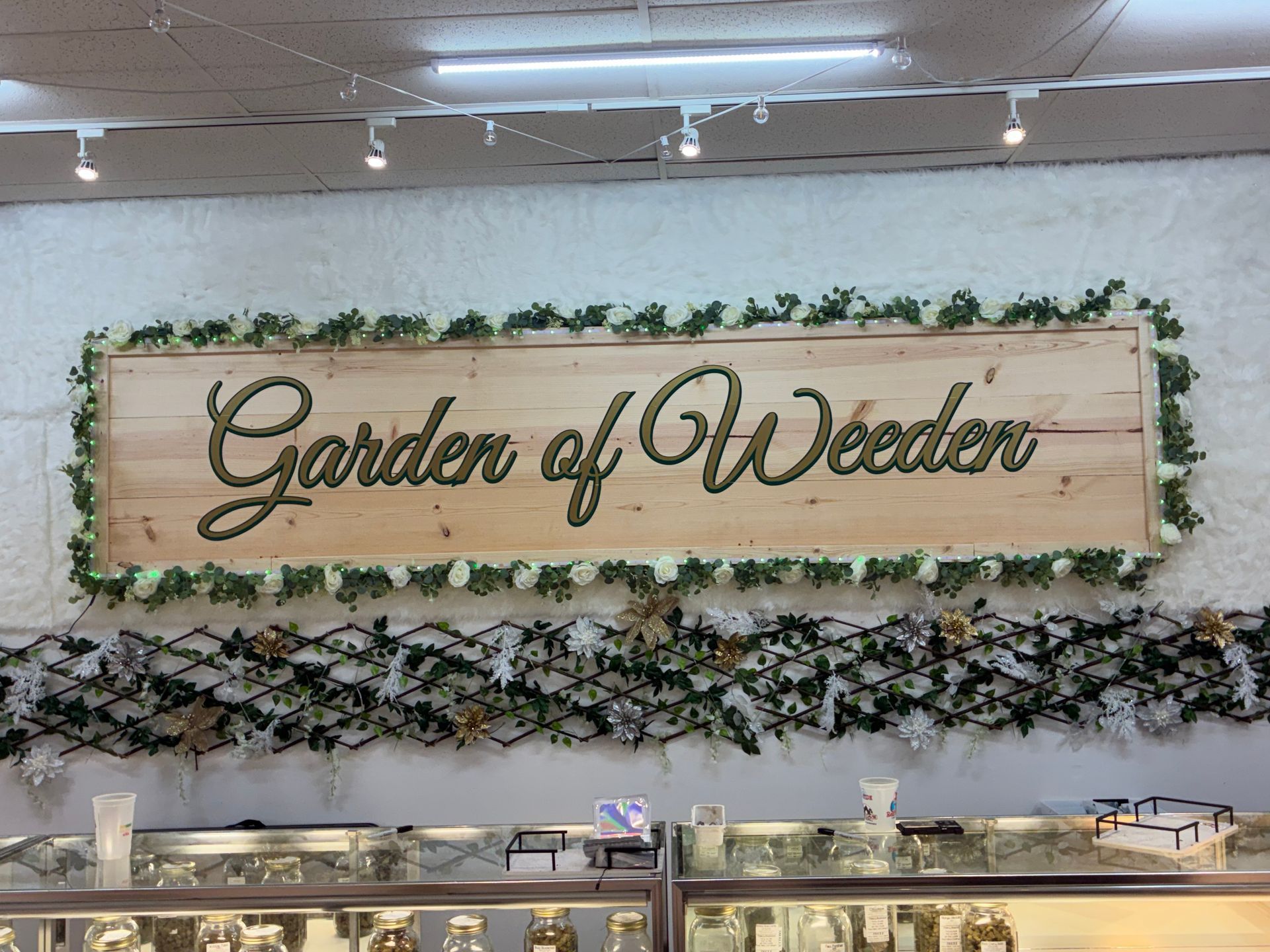 “Garden of Weeden” sign on a wood panel, framed by greenery above a buffet counter
