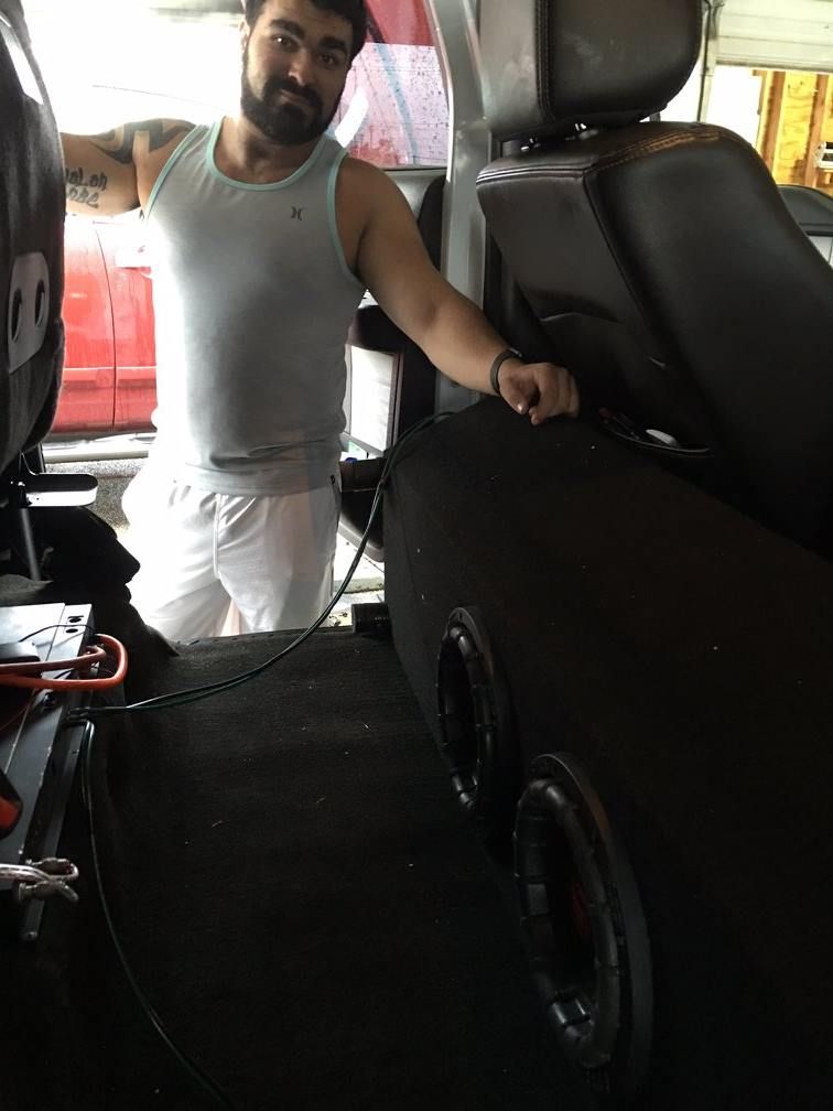 A man is standing in the back seat of a car.