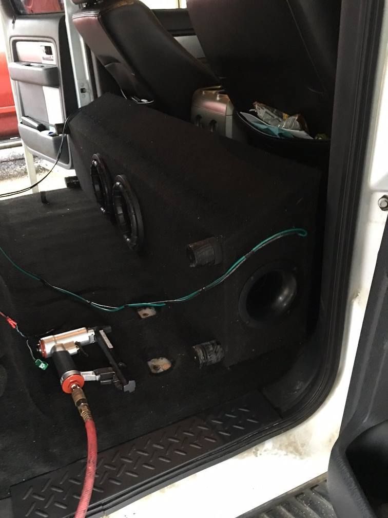A white truck with a subwoofer in the back seat.