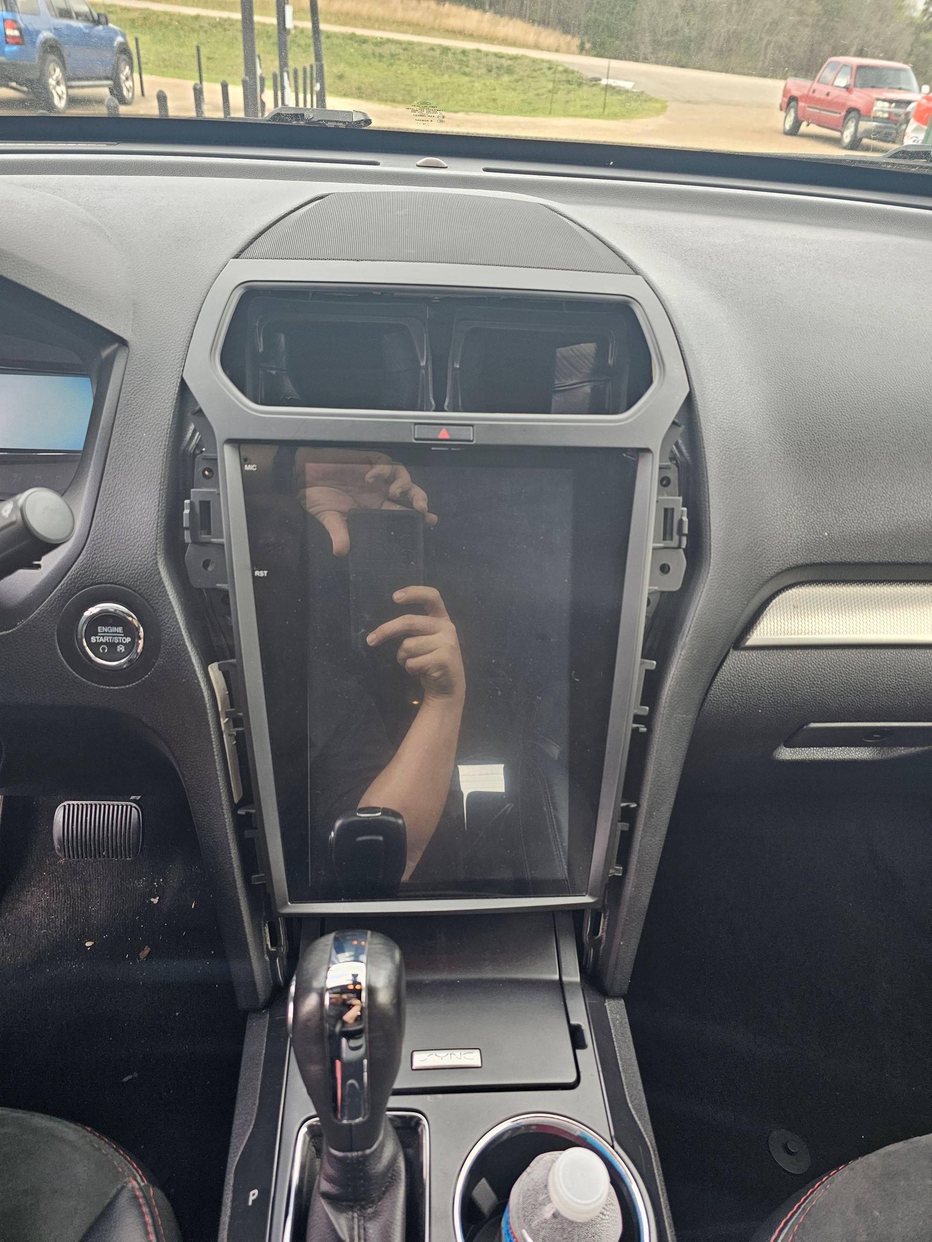 A person is taking a picture of their reflection in the dashboard of a car.
