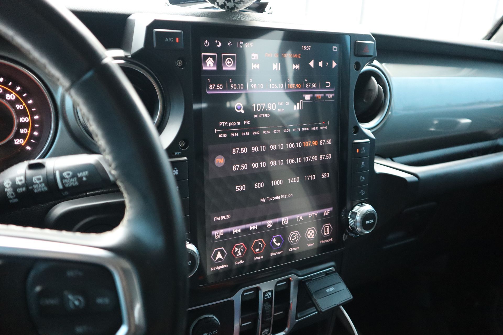 A car dashboard with a steering wheel and a touchscreen display.