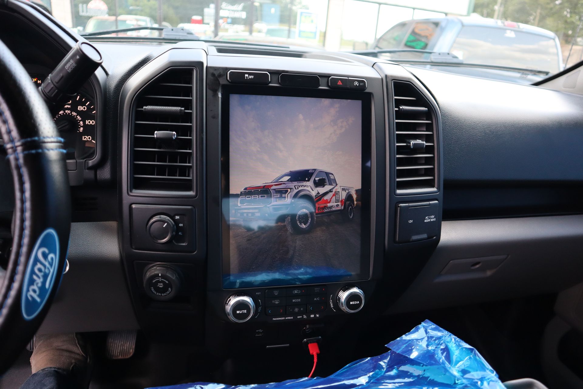 A person is sitting in a car with a ford logo on the steering wheel