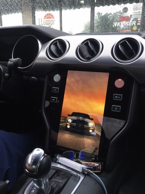 A car dashboard with a tablet displaying a car on the screen