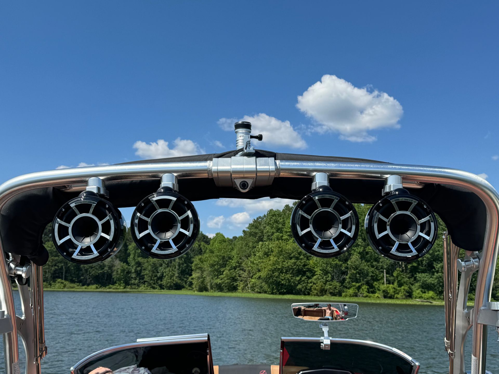 A boat with speakers on top of it is floating on a lake.
