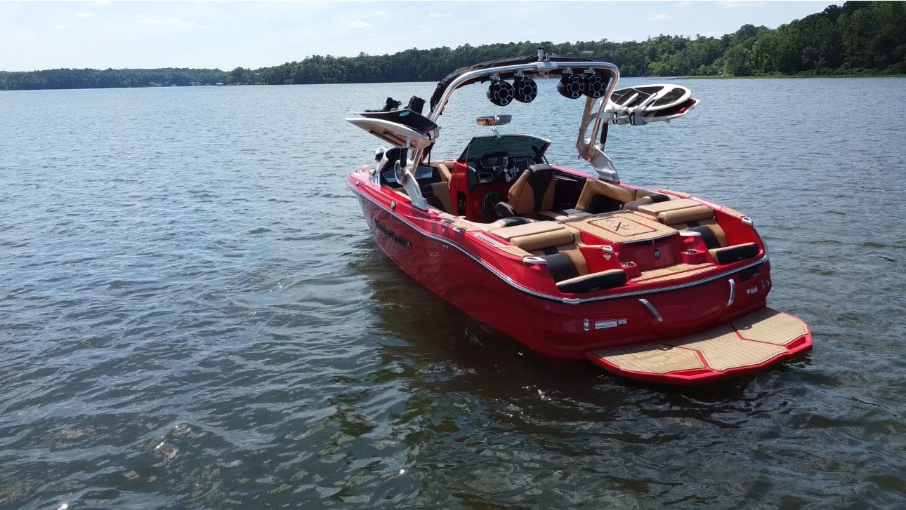 A red boat is floating on top of a lake.