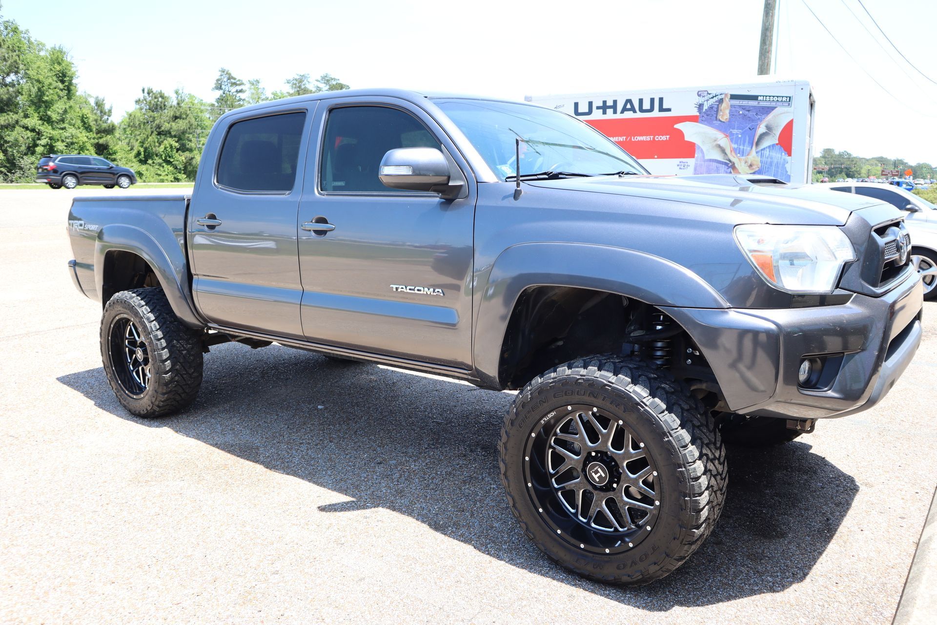 A toyota tacoma truck is parked in a parking lot next to a u-haul truck.