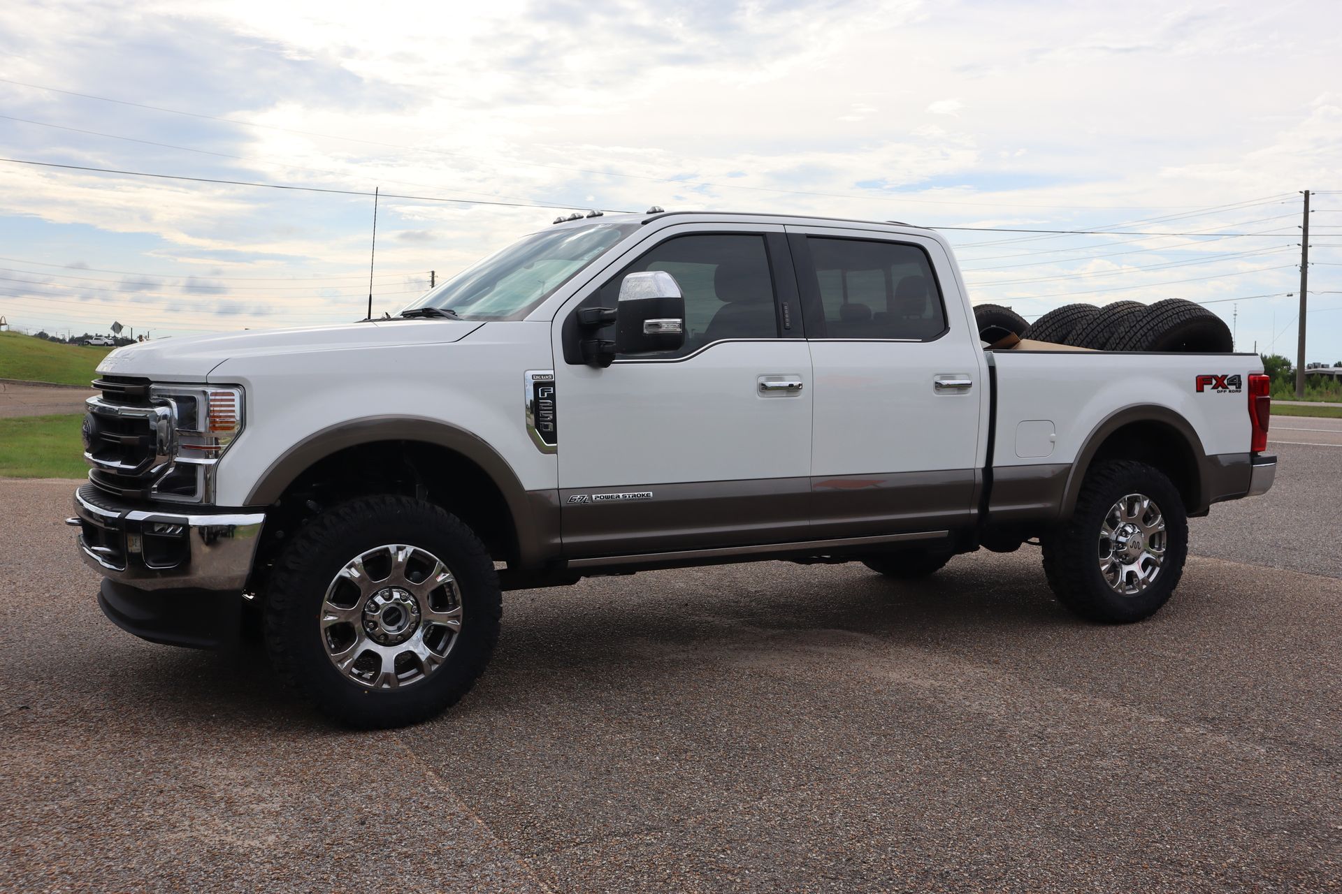 A white pickup truck is parked on a gravel road.
