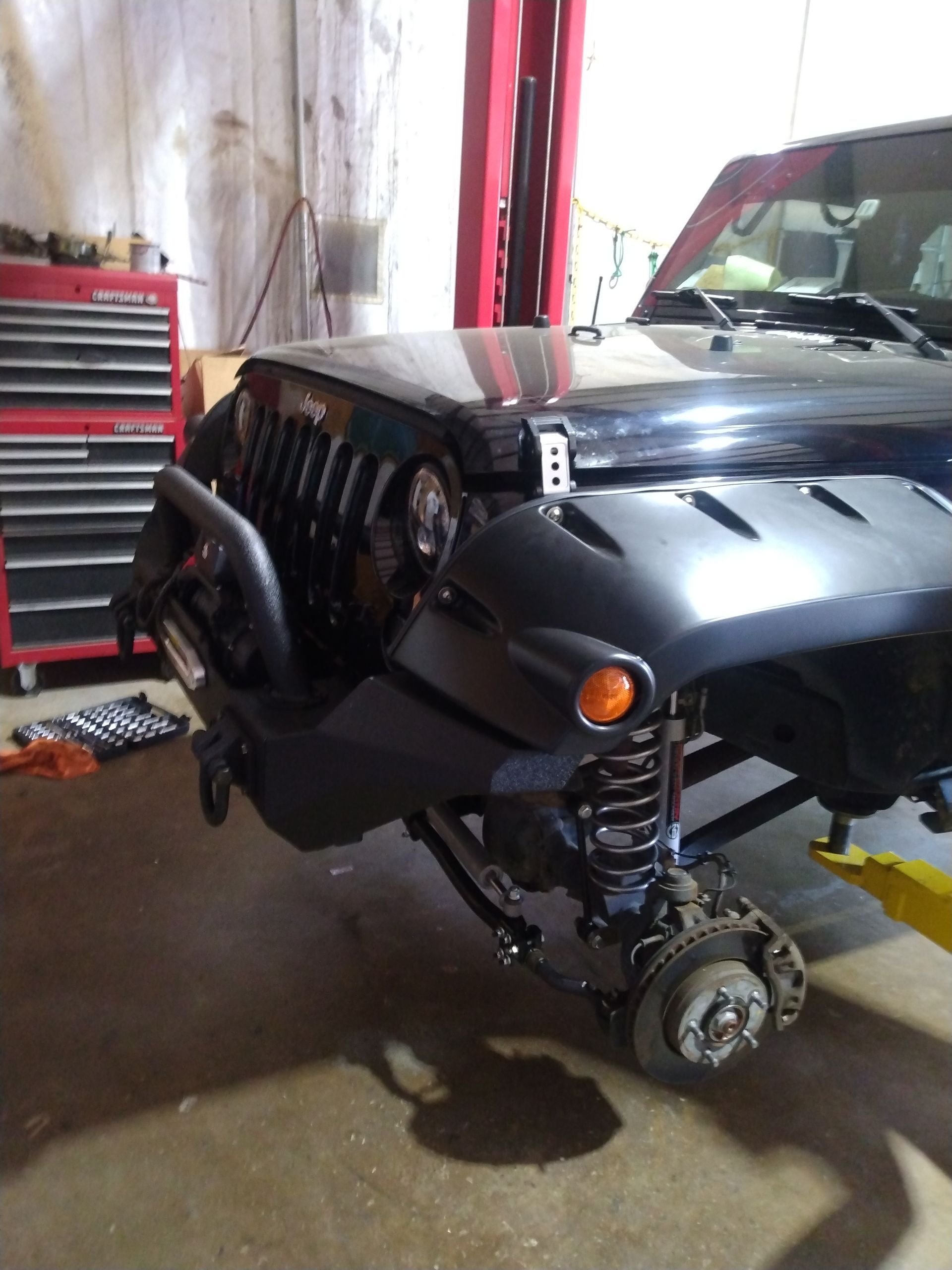 A black jeep is sitting on a lift in a garage