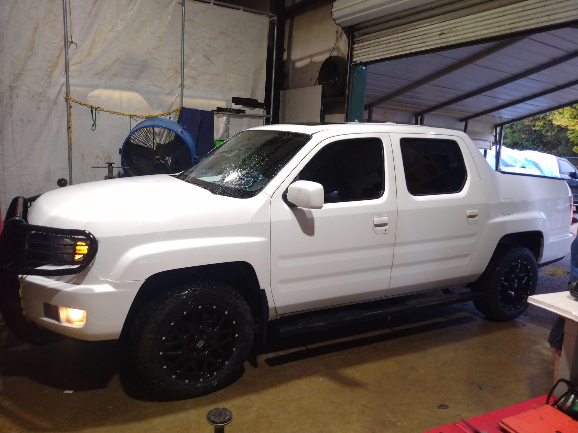 A white truck with black wheels is parked in a garage.