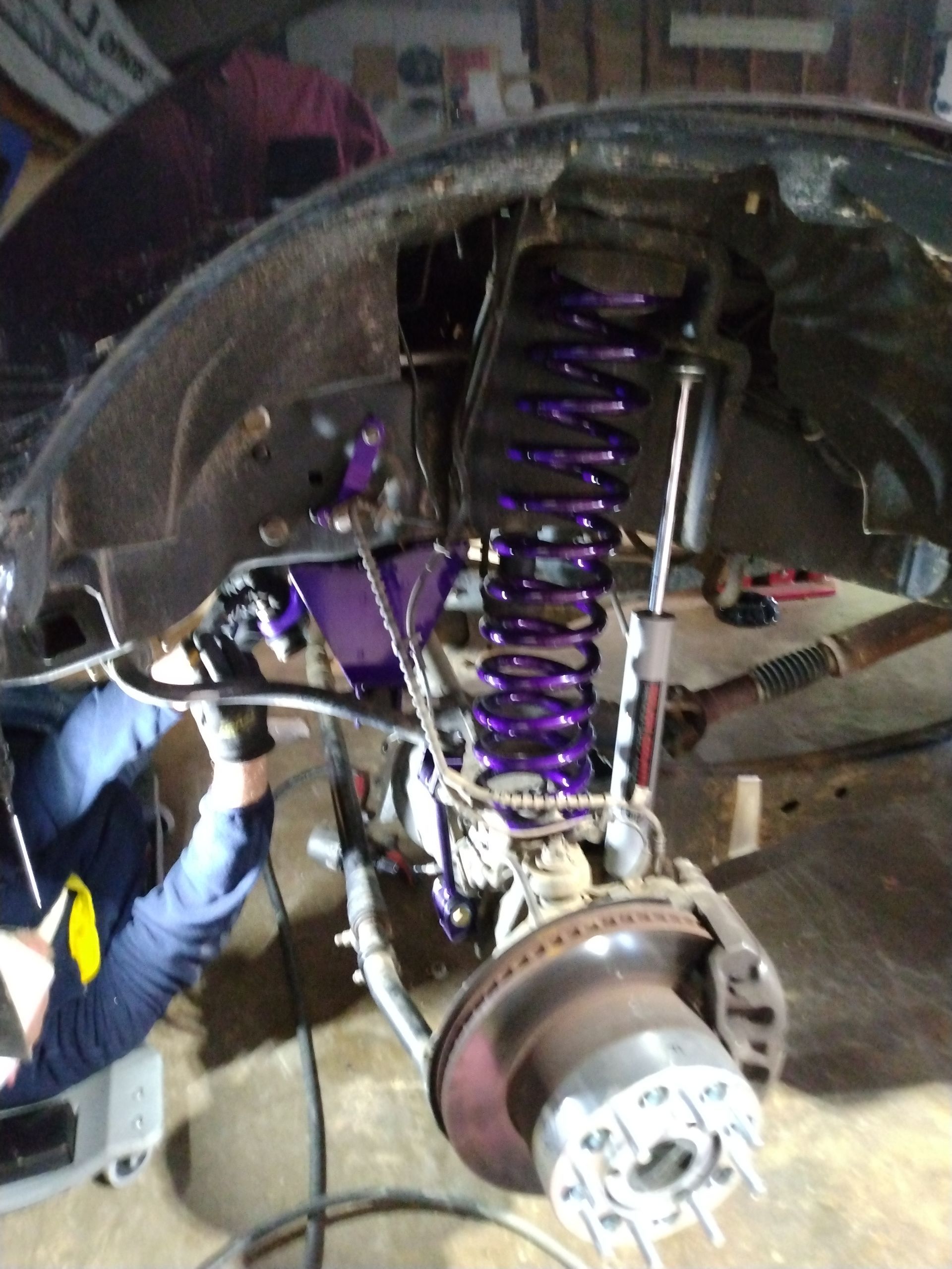 A person is working on a car with purple springs