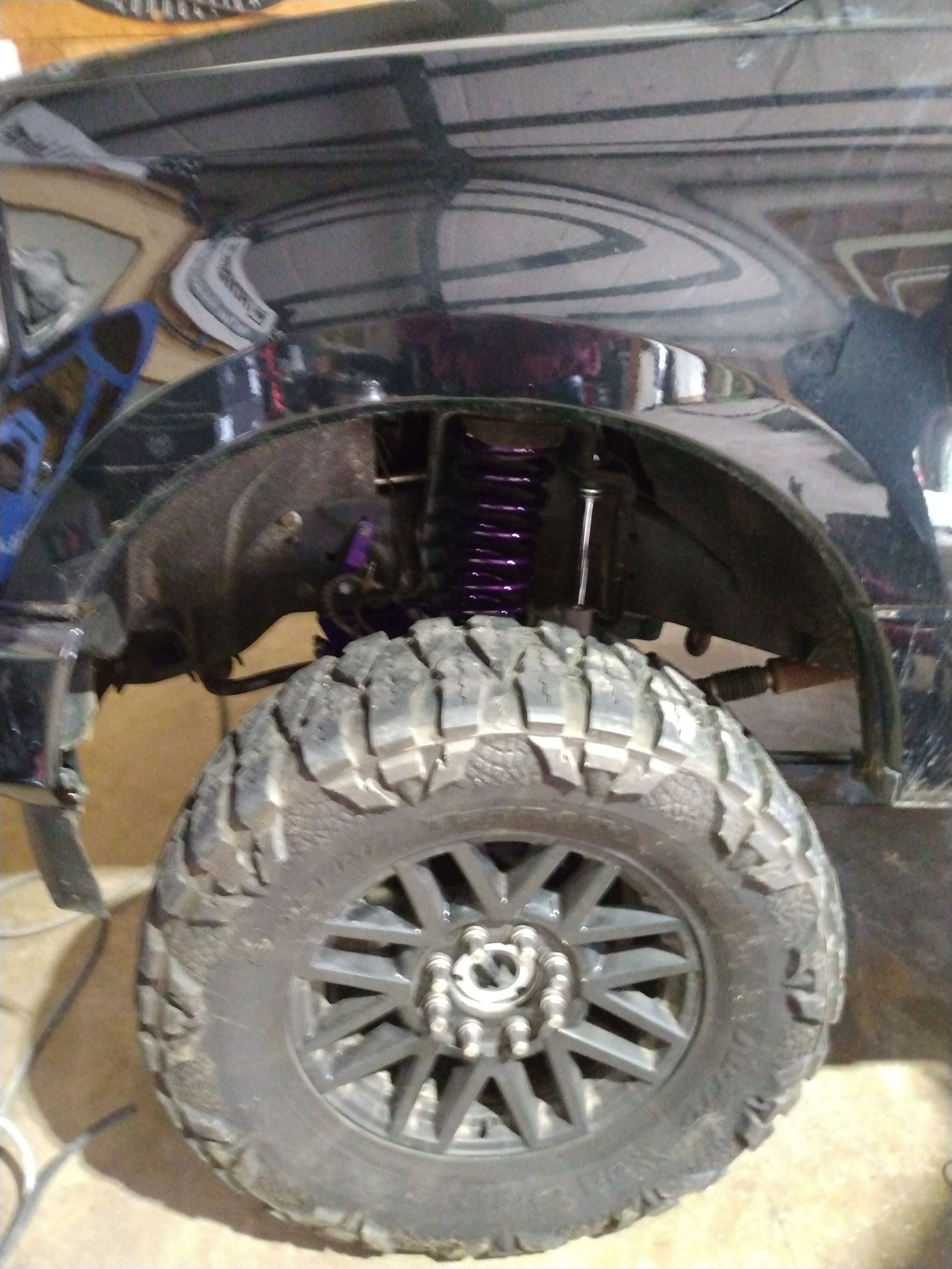 A black truck with a large tire is parked in a garage.