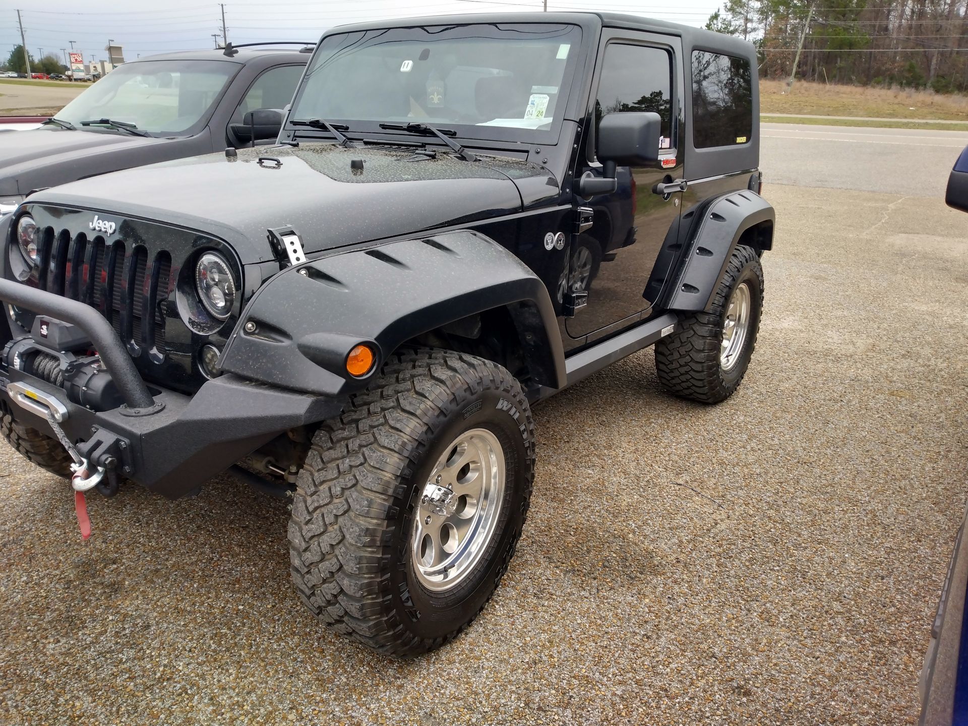 A black jeep wrangler is parked in a parking lot.