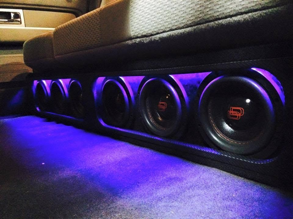 A purple light is shining on a subwoofer in a car