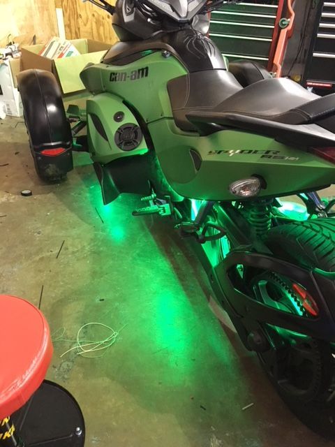 A green can-am motorcycle is parked in a garage