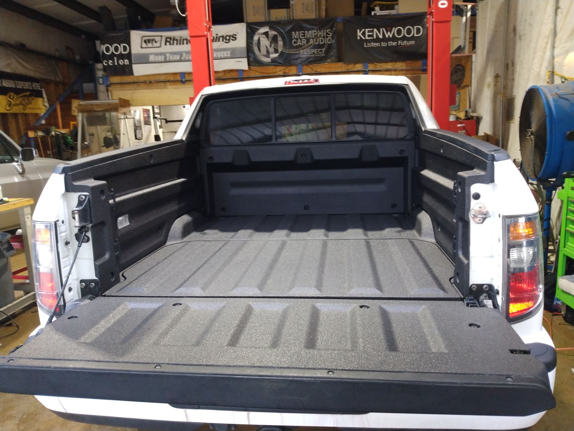 A white truck is parked in a garage with the bed open