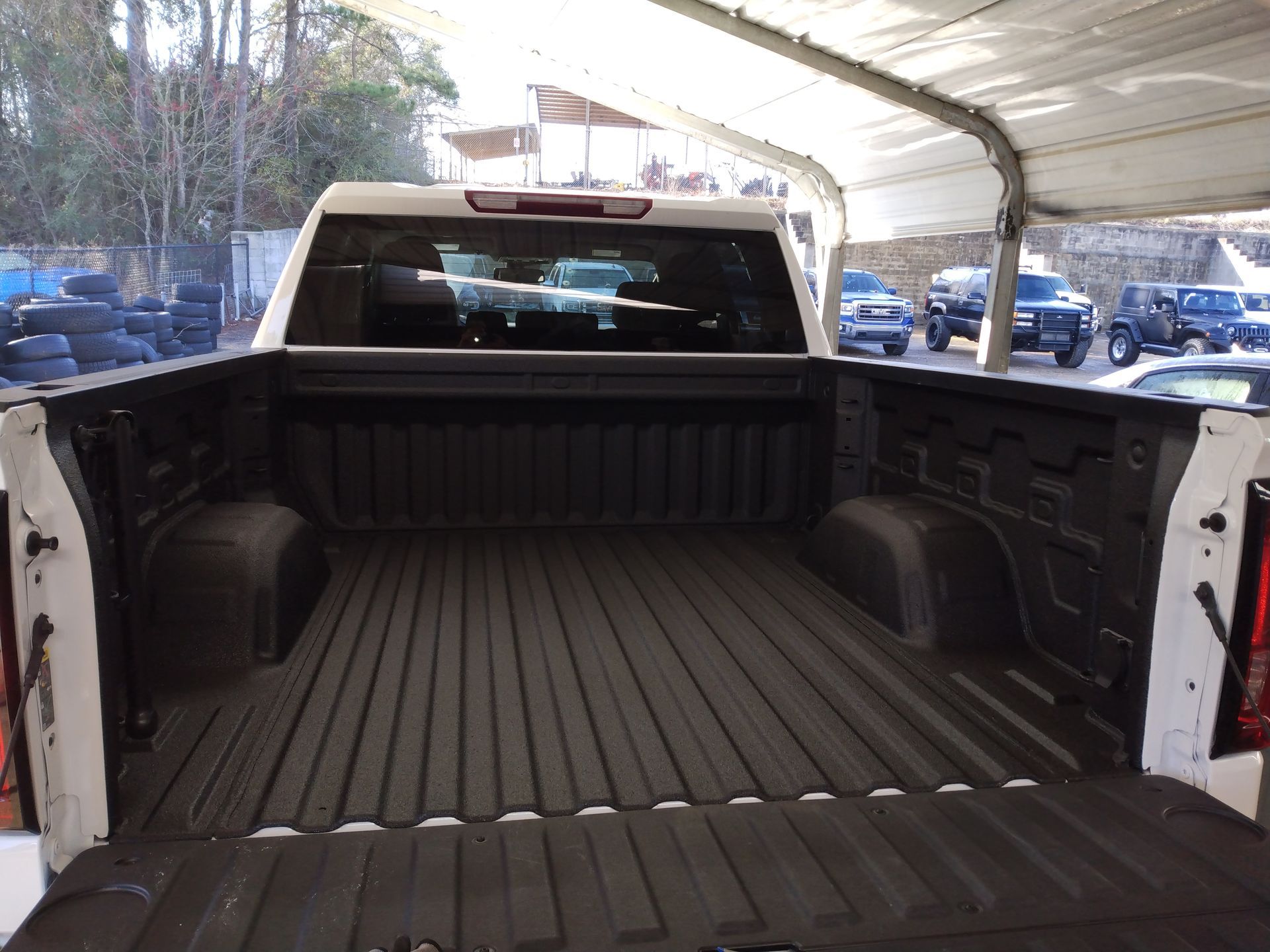A white truck is parked under a tent in a parking lot