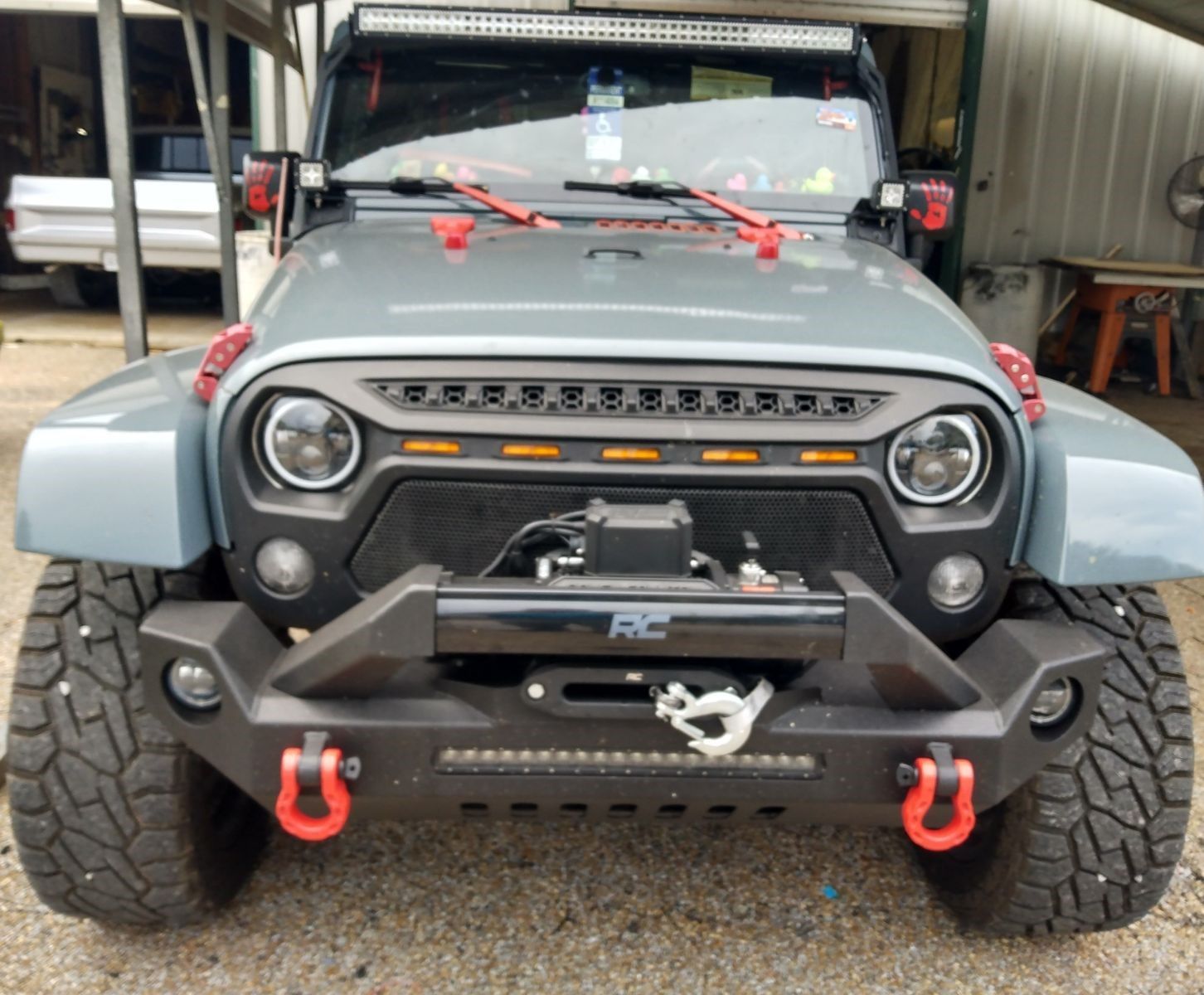 A grey jeep with a black bumper and red hooks