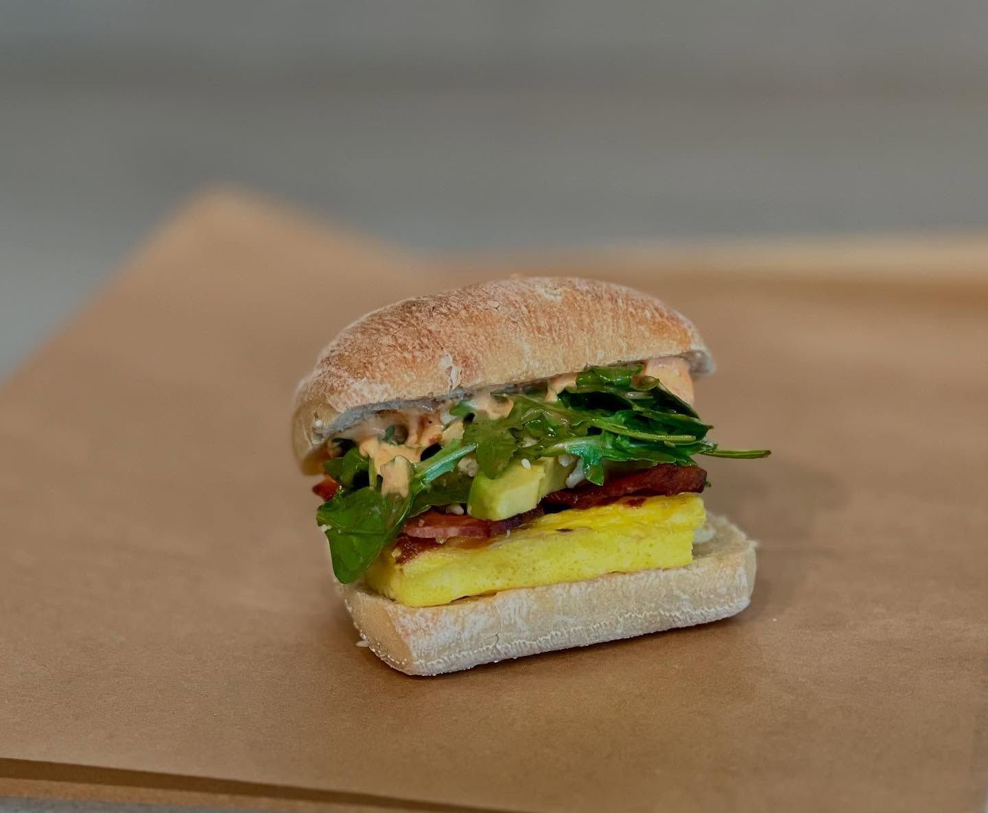 Sandwich with egg, bacon, and arugula on a roll.
