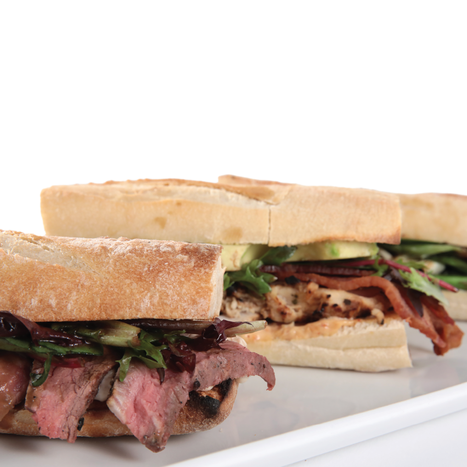 Two sandwiches on a white plate with a white background